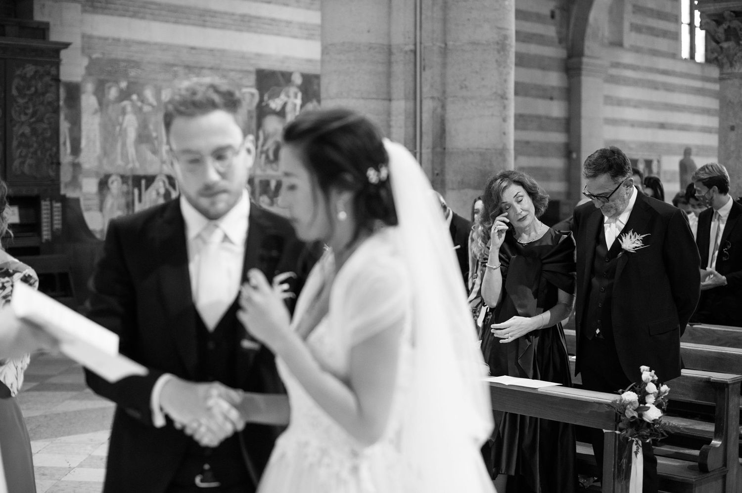 Black and white photo of wedding ceremony exchange inside historic church interior.