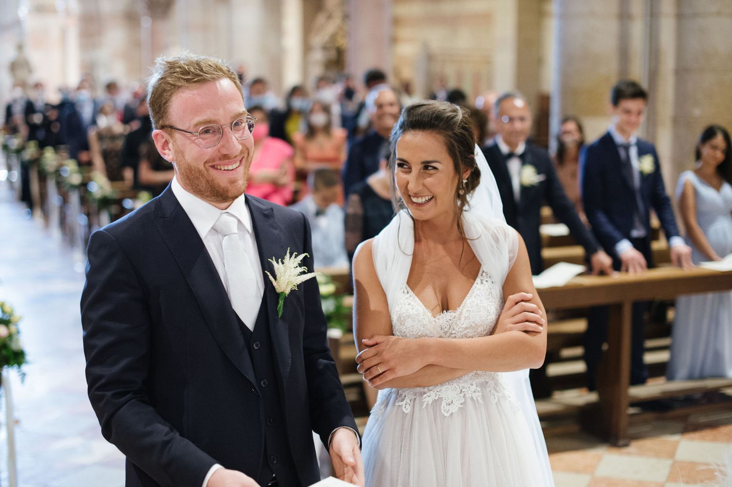 Happy wedding moment inside historic Italian church with striped marble columns and architectural details.