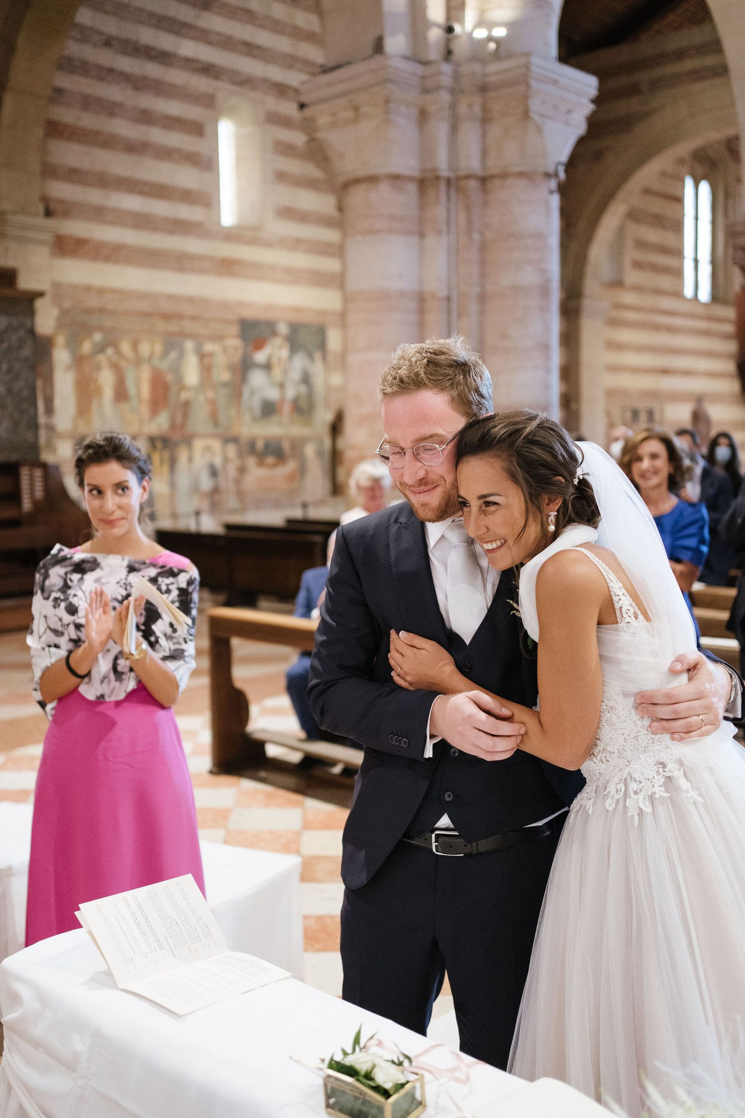 A couple shares a joyful moment during their wedding ceremony inside a historic church with striped walls.