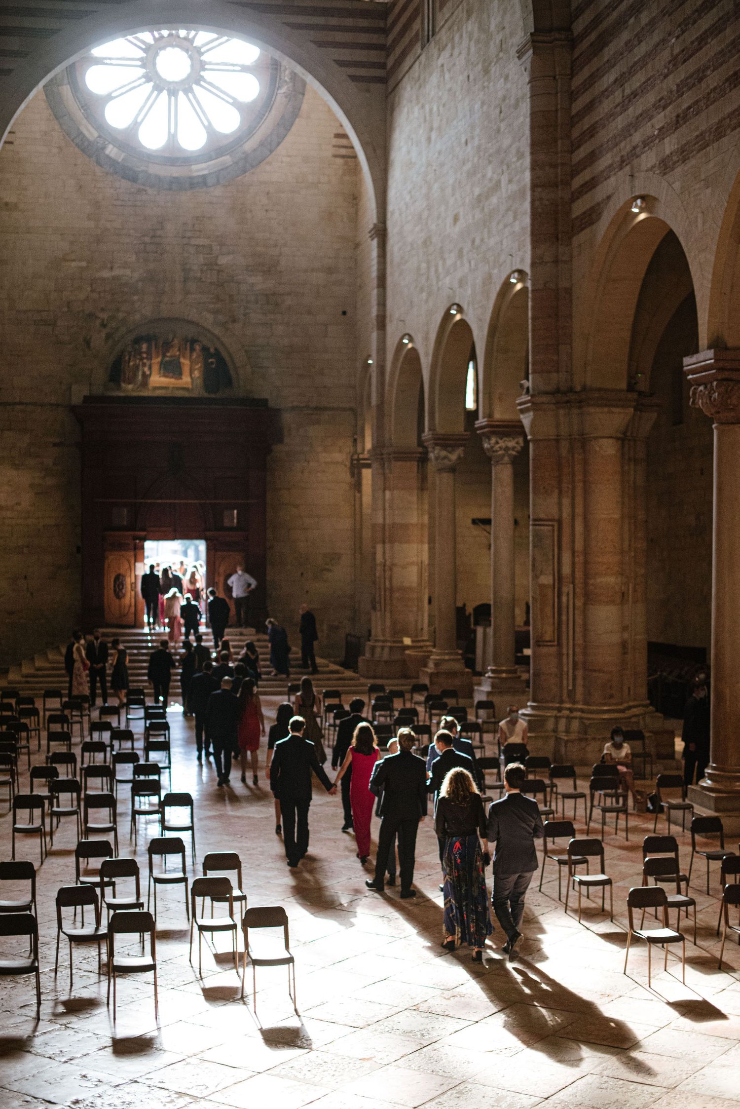 Sunlight streams through a rose window in a grand cathedral with rows of empty chairs.