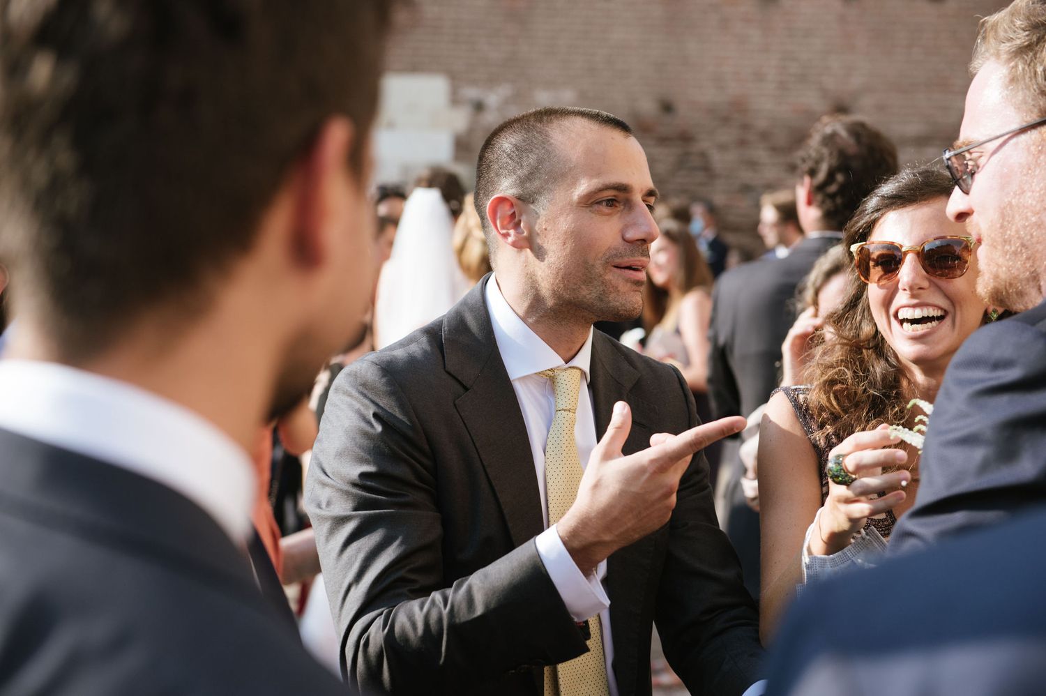 Wedding guests share animated conversations during an outdoor reception.