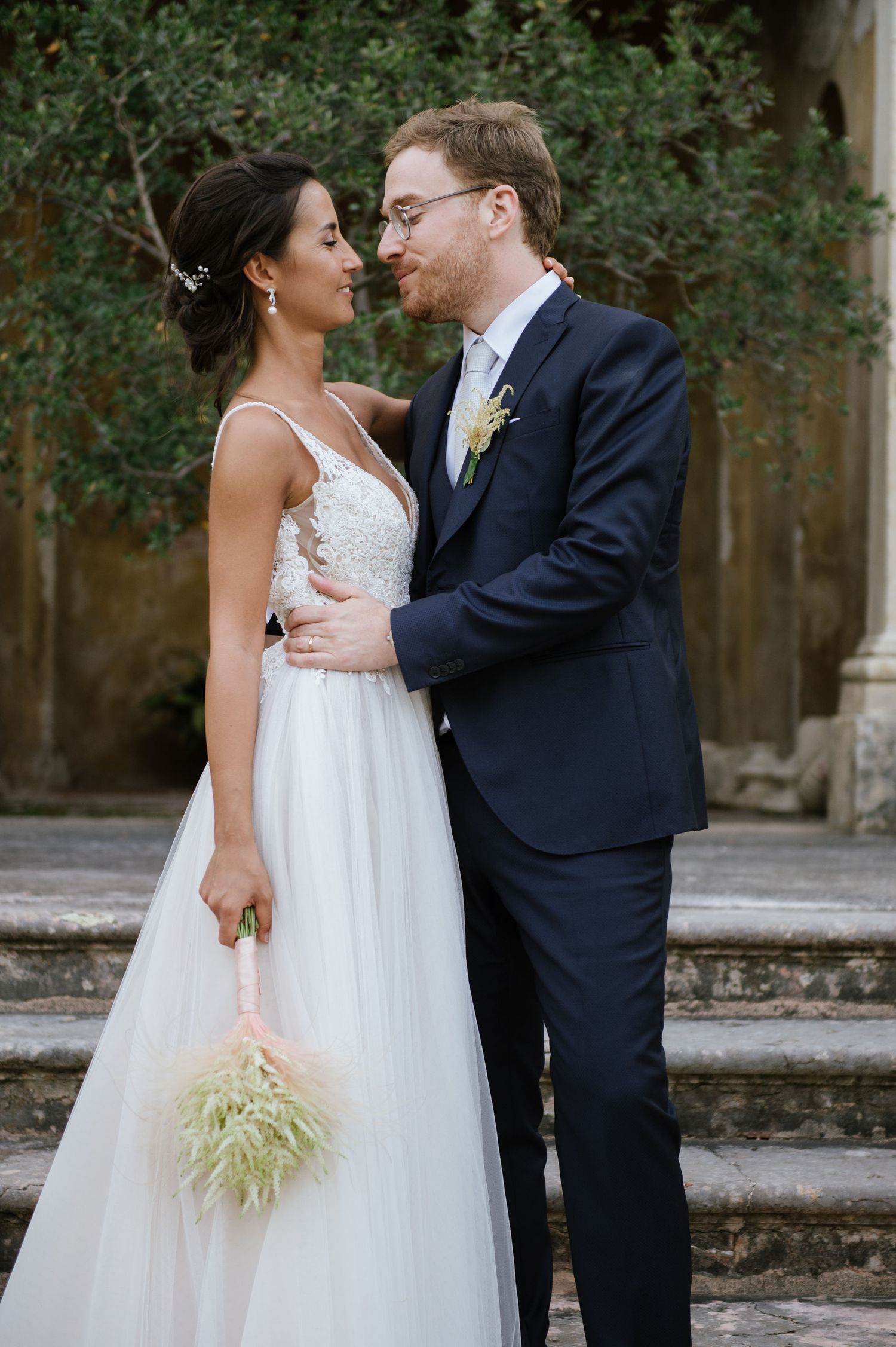 A romantic wedding moment captured on vintage stone steps with an olive tree backdrop.