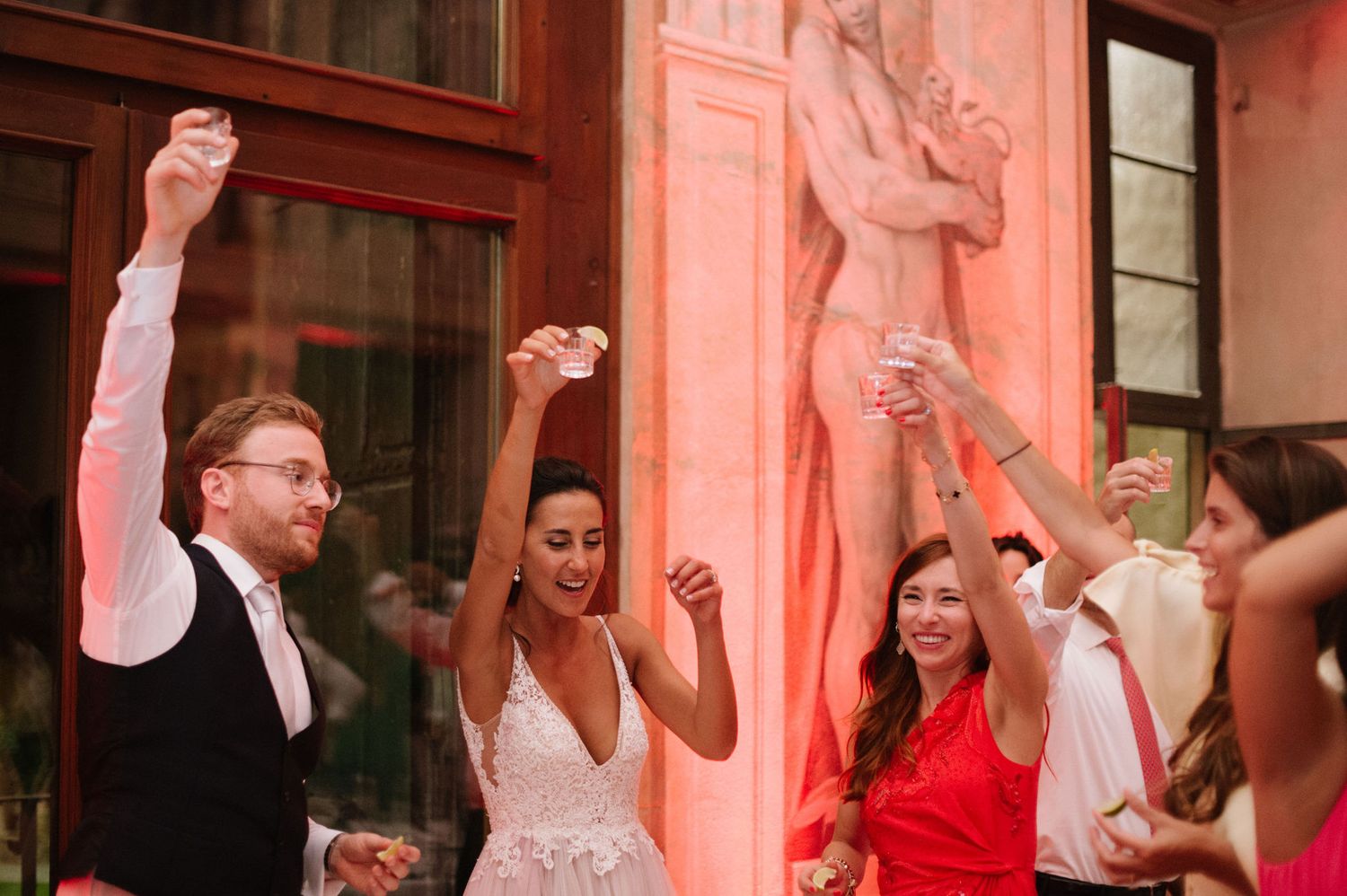 Wedding celebration with guests raising hands in joyful dance at elegant venue.