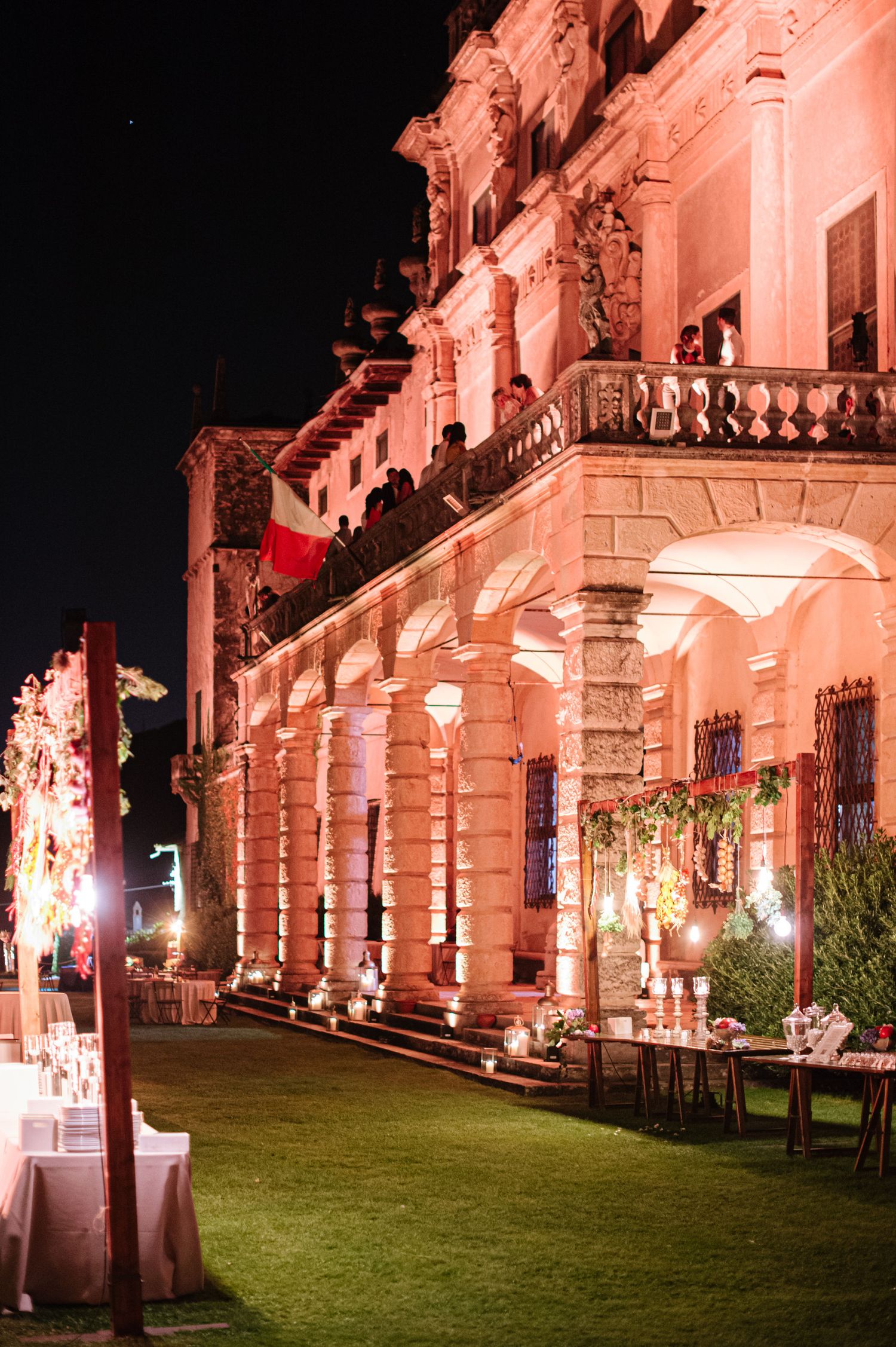 Historic Italian villa illuminated in pink lighting for evening wedding reception.