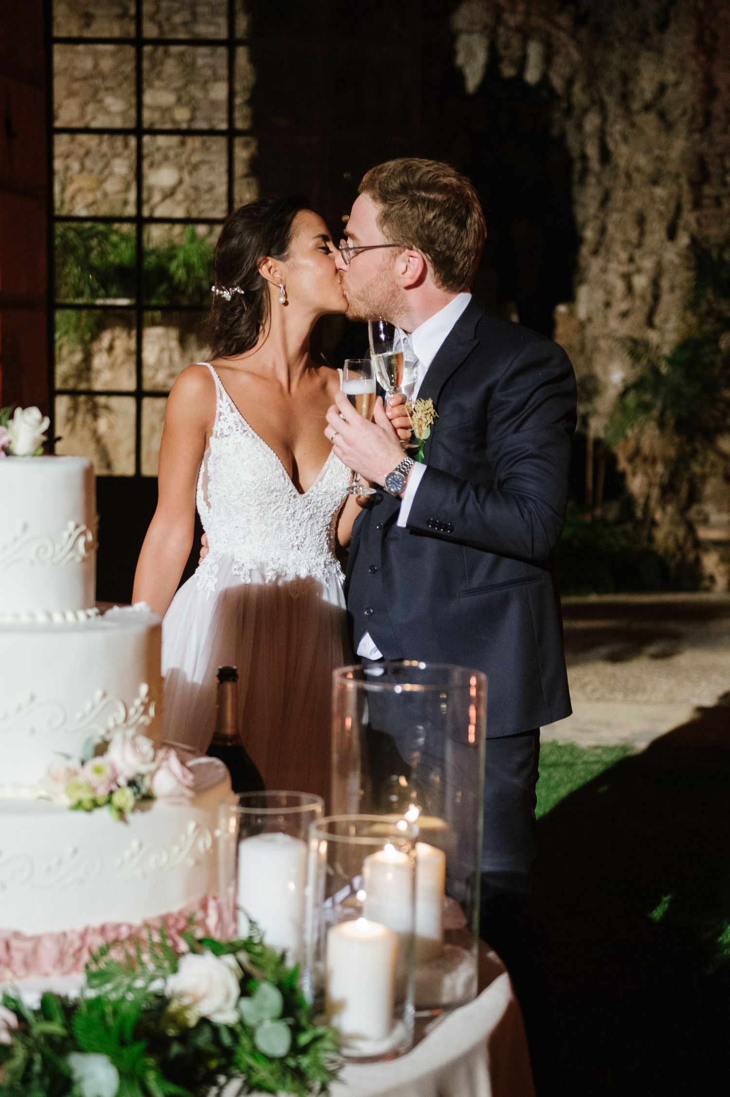 A romantic wedding cake cutting moment with elegant candles and floral decorations.