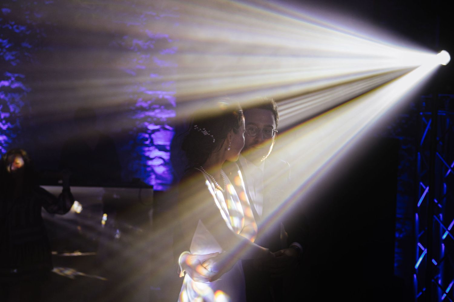 Dramatic white spotlight beams cutting through smoke at an evening event.