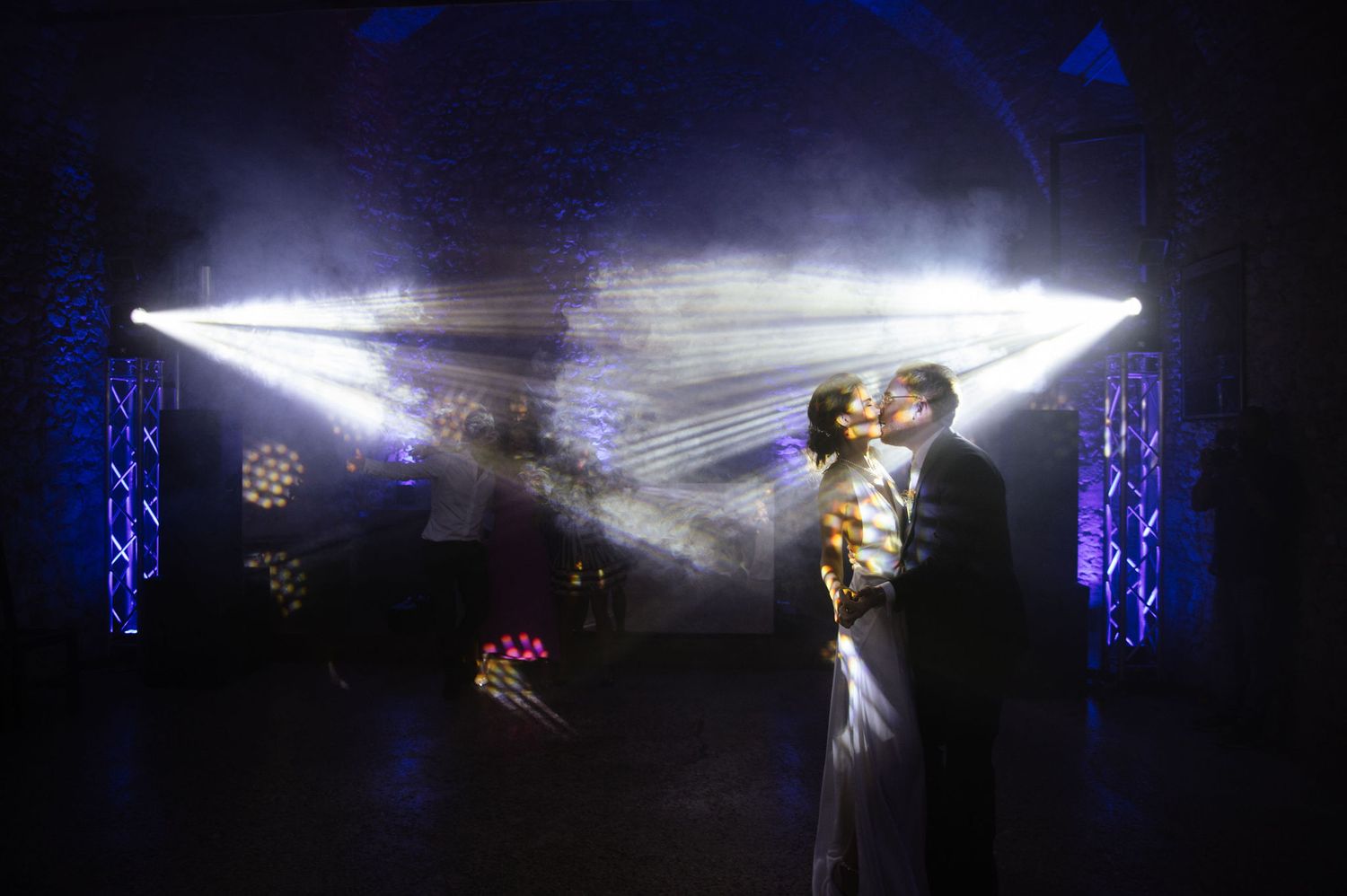 Dramatic spotlights create a magical atmosphere during a wedding dance.