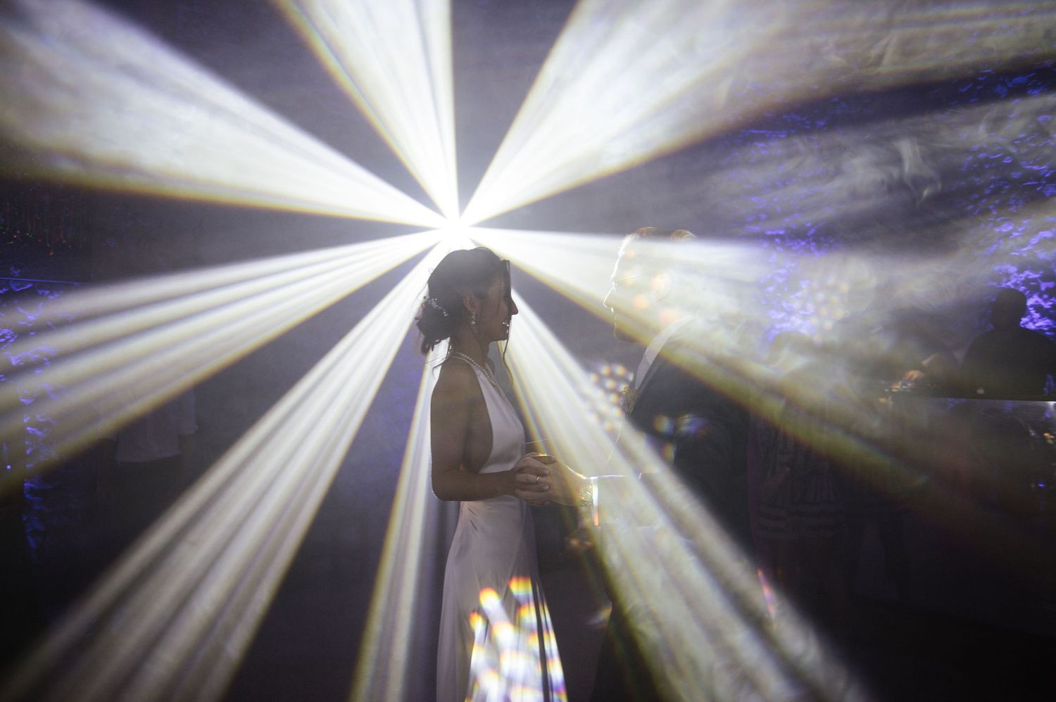 Silhouette surrounded by radiating white spotlight beams creating a starburst effect.
