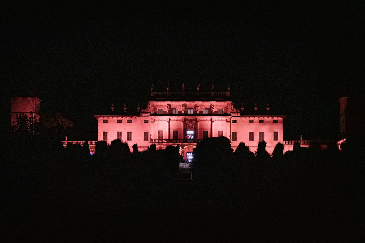Grand mansion illuminated in dramatic red lighting against the night sky.