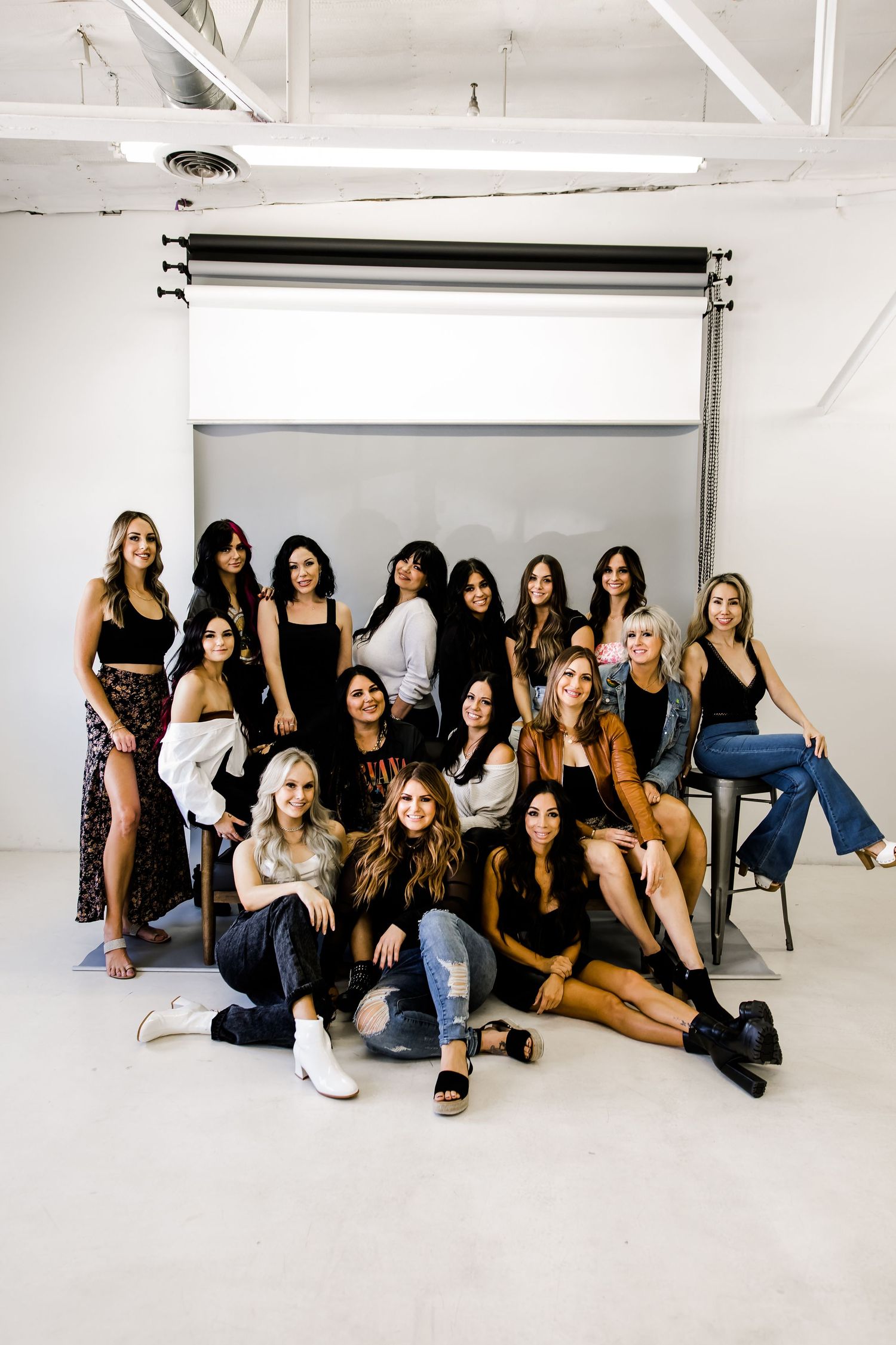 Industrial white studio with fifteen salon working women posing together uniquely for a marketing and branding photoshoot.
