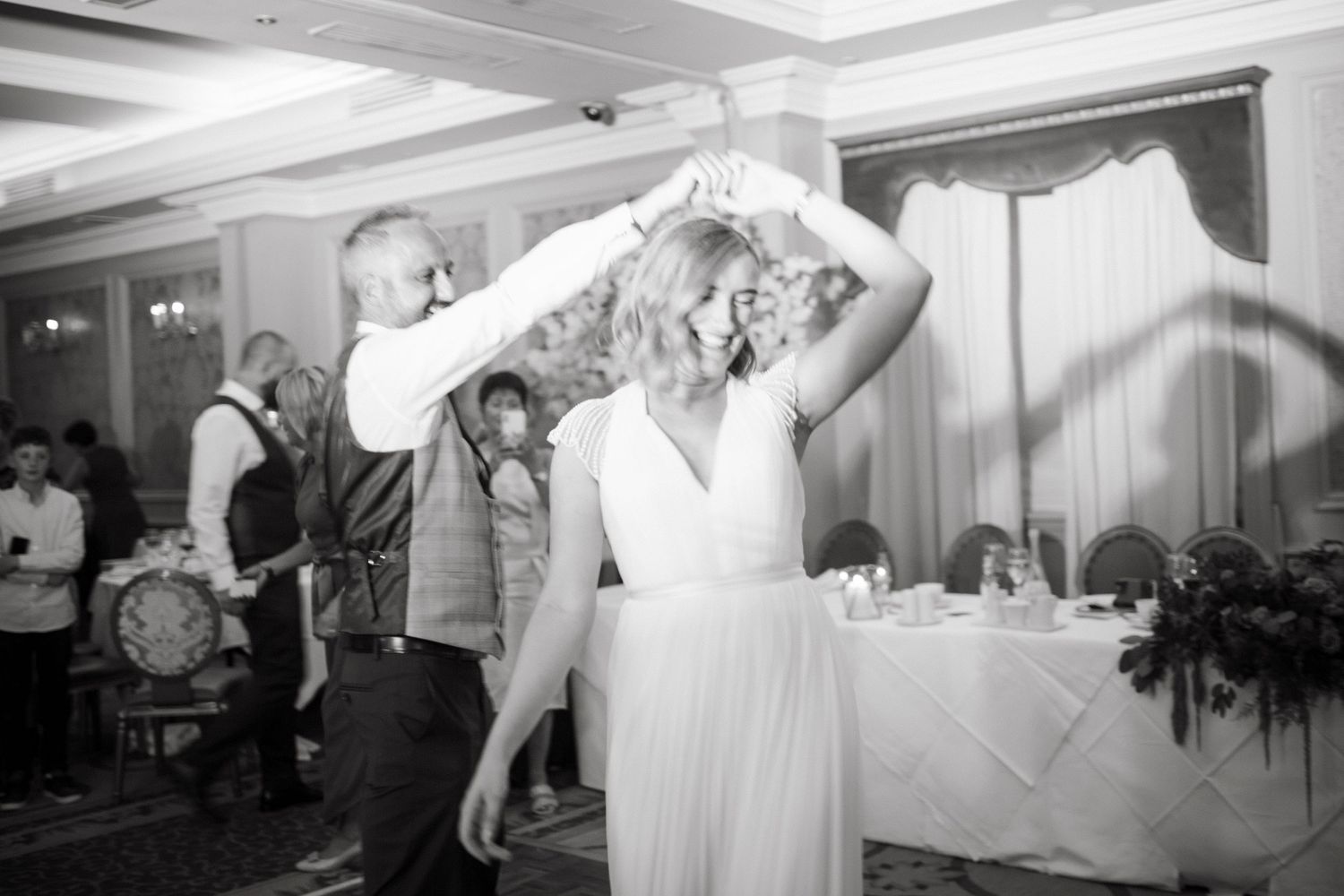 Couple dancing together at a wedding reception in black and white.