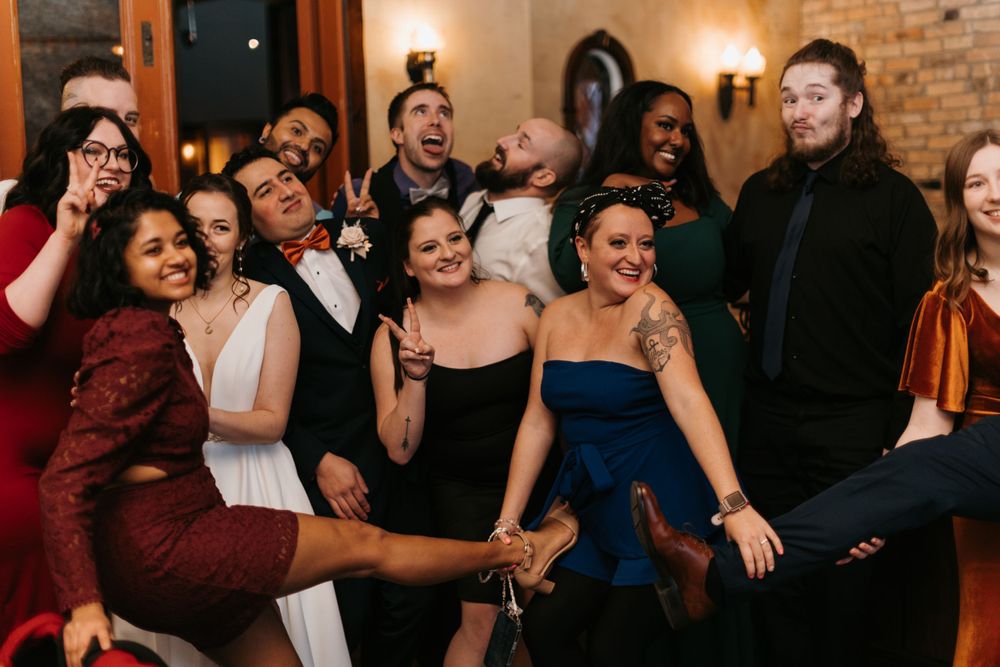 Joyful wedding guests laugh and pose together for a lively group photo at the reception celebration.
