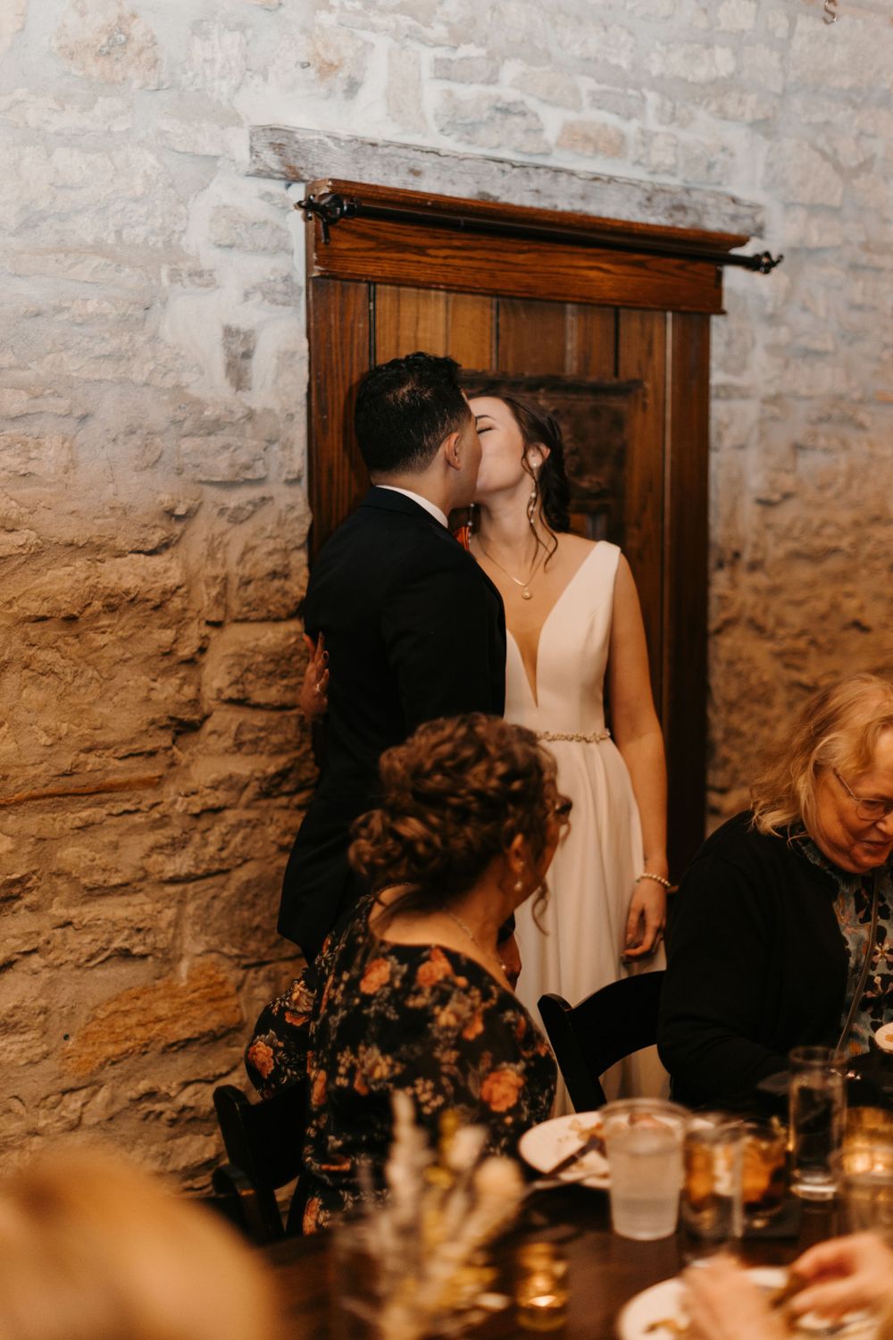 Bride and groom sharing a kiss in a doorway at their rustic stone wedding venue.
