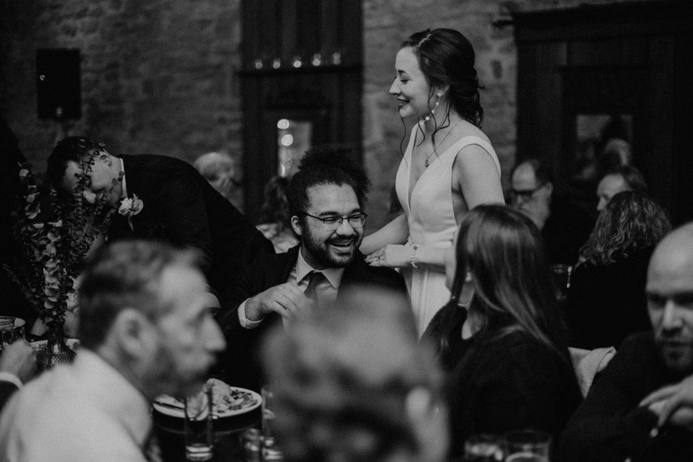 Black and white photo of wedding guests sharing a joyful moment at the reception dinner.