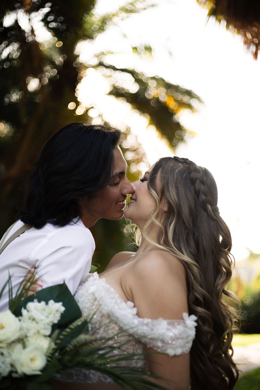 An intimate wedding portrait showing a loving kiss against a dreamy sunset backdrop.