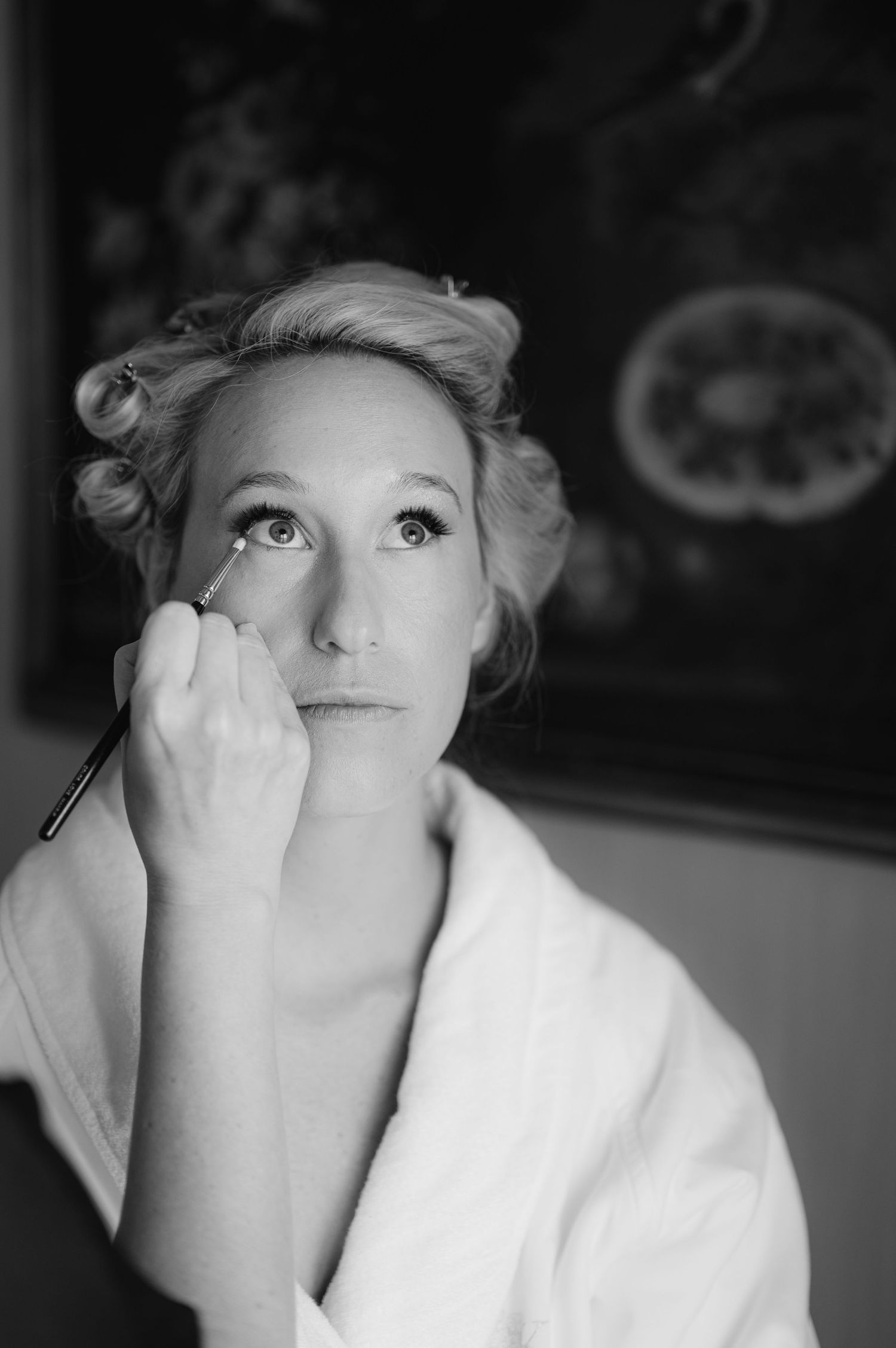 Black and white portrait showing makeup application in classic style.