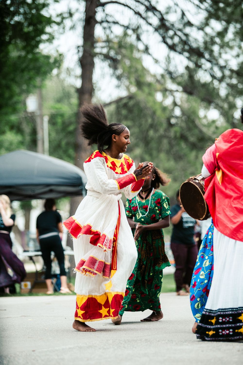 A lively cultural celebration with people in traditional white and red dresses dancing outdoors.