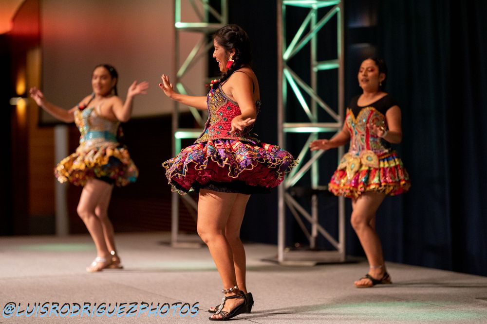Dancers in colorful ruffled dresses perform on stage during a cultural show.