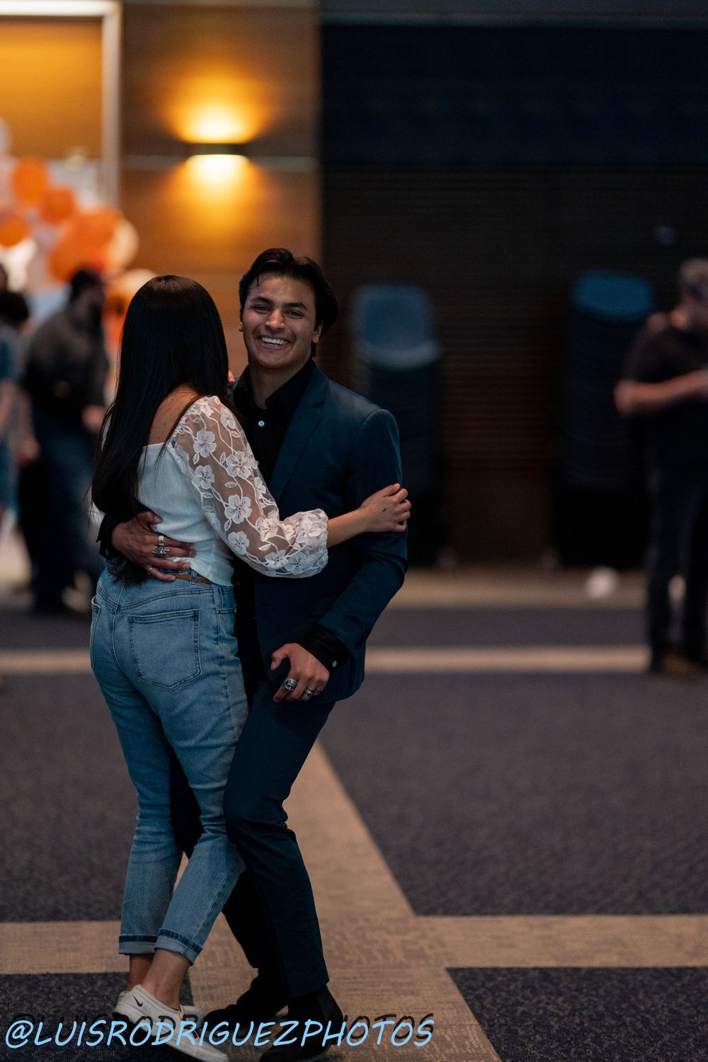 A couple shares a joyful embrace at an indoor event.