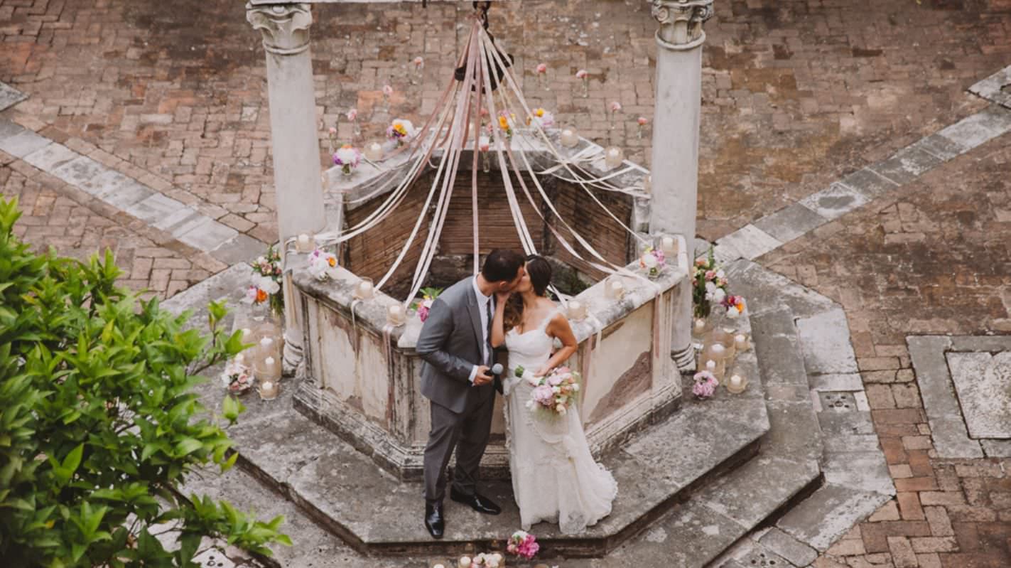 Wedding couple sharing an intimate moment in a stone gazebo courtyard.