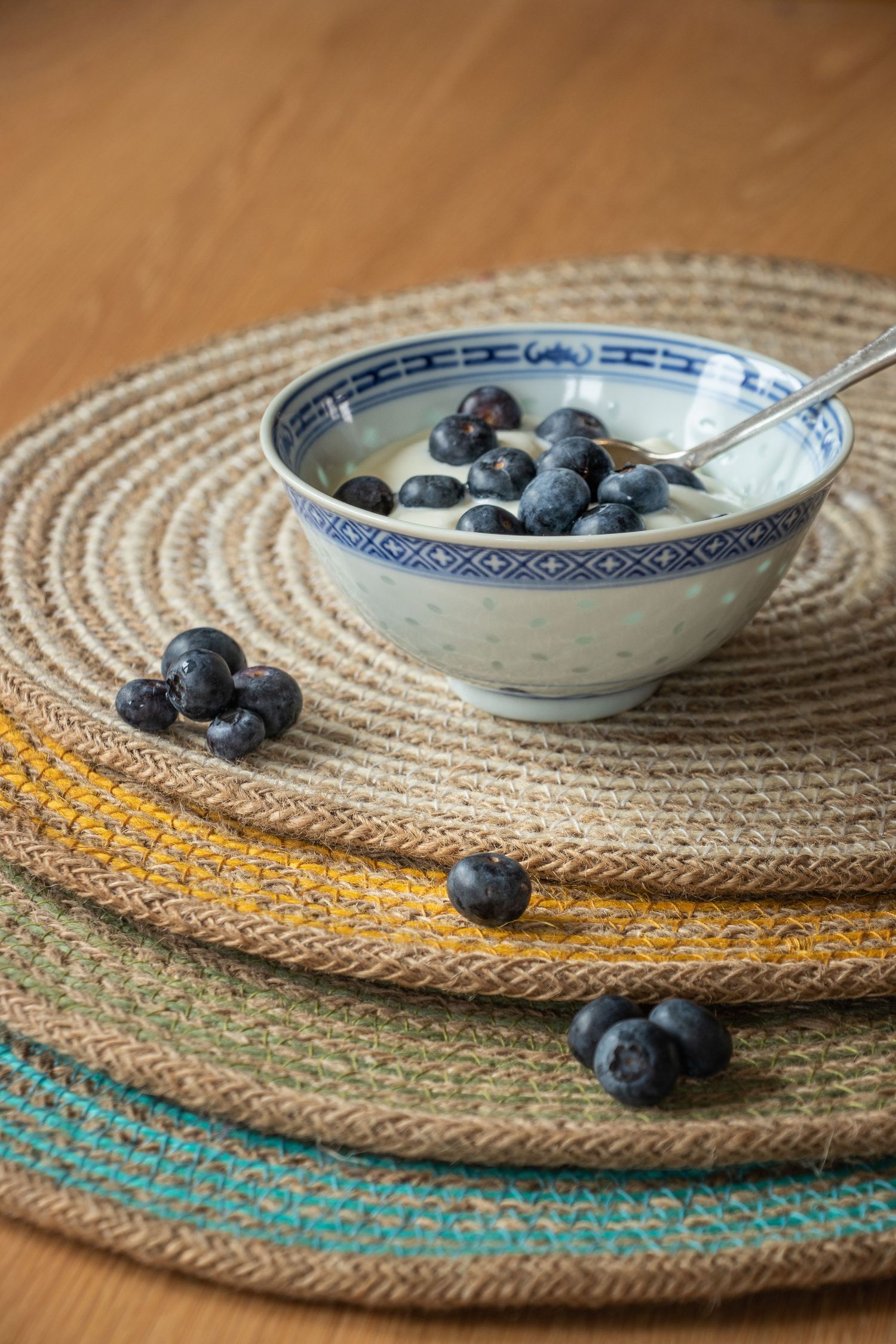 blueberries and yogurt in a small dish on a stack of coloured mats
