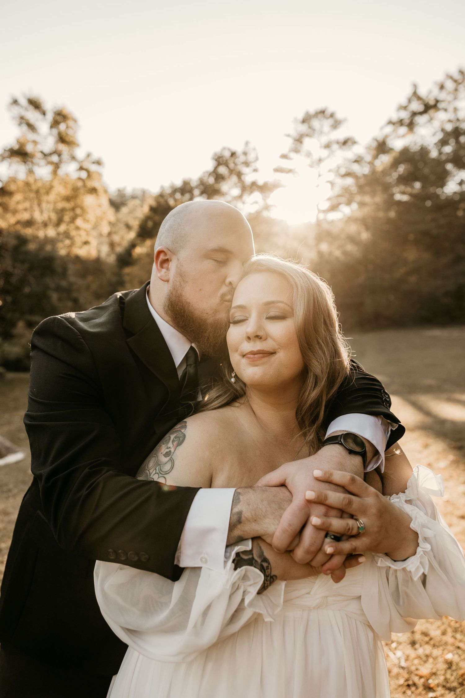 Sunset wedding portrait with gentle embrace and backlit golden glow.