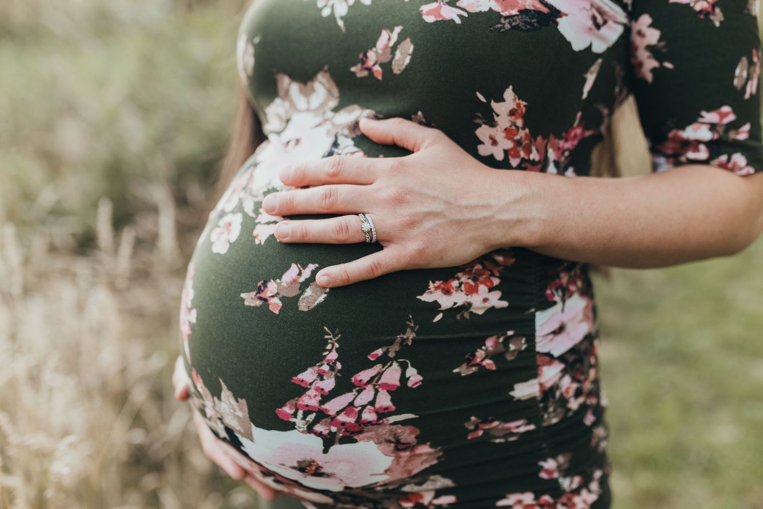 Close up of pregnant belly and hand with wedding ring
