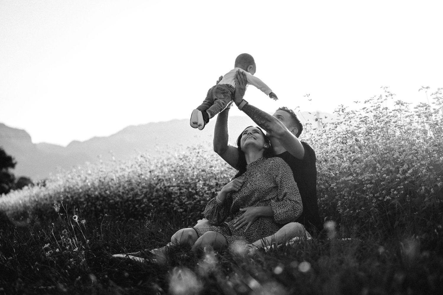 People playing and running through a blooming wildflower field at sunset.