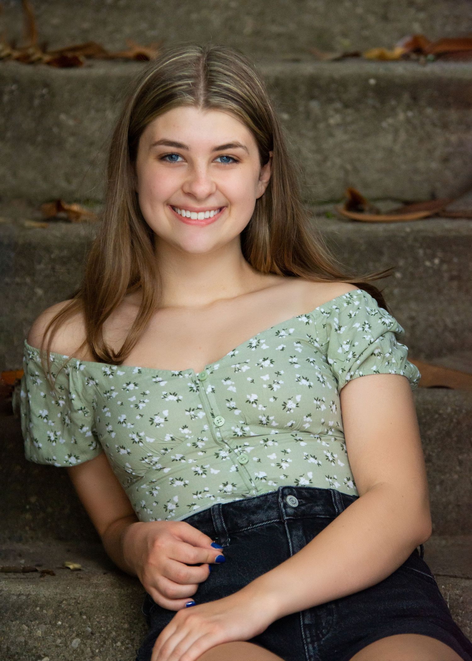 Portrait of someone in a mint green floral top and dark denim sitting on concrete steps. Senior photography Batavia Cincinnati Ohio