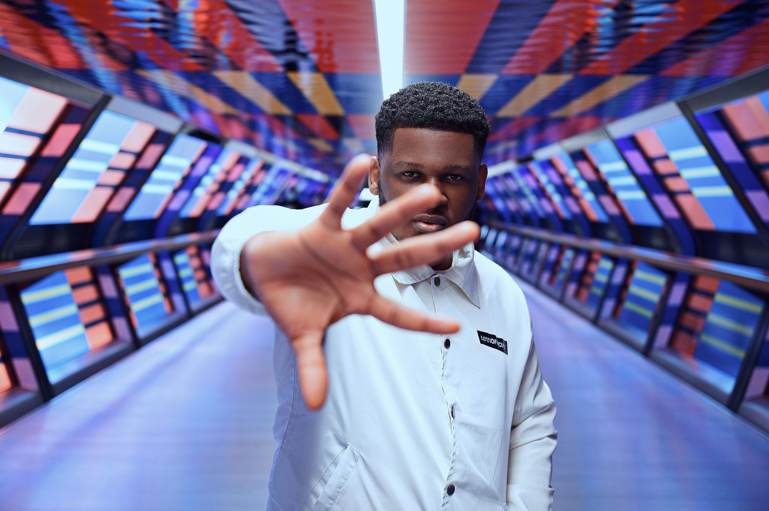 How to pose male in London: Black  male posing in a colourful tunnel.