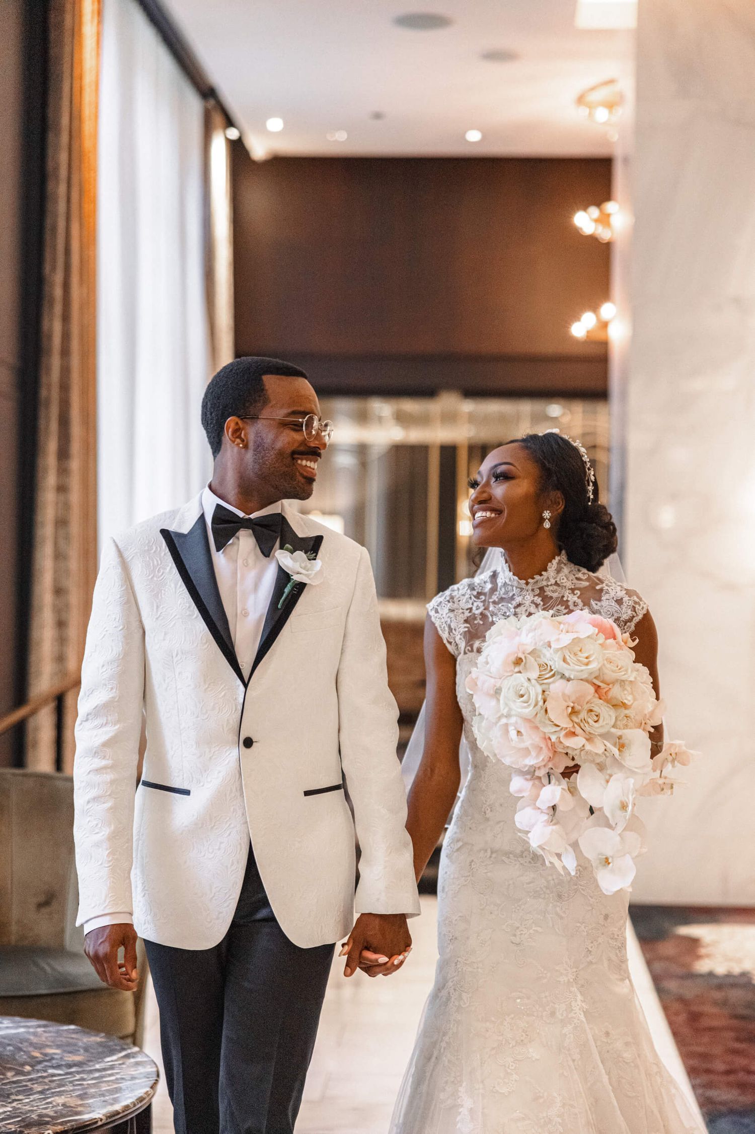 Newlyweds in elegant attire share a joyful moment in an indoor venue.