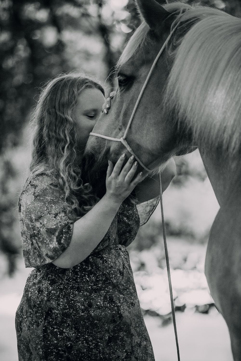 Tender moment between a horse and person sharing an intimate connection in black and white.