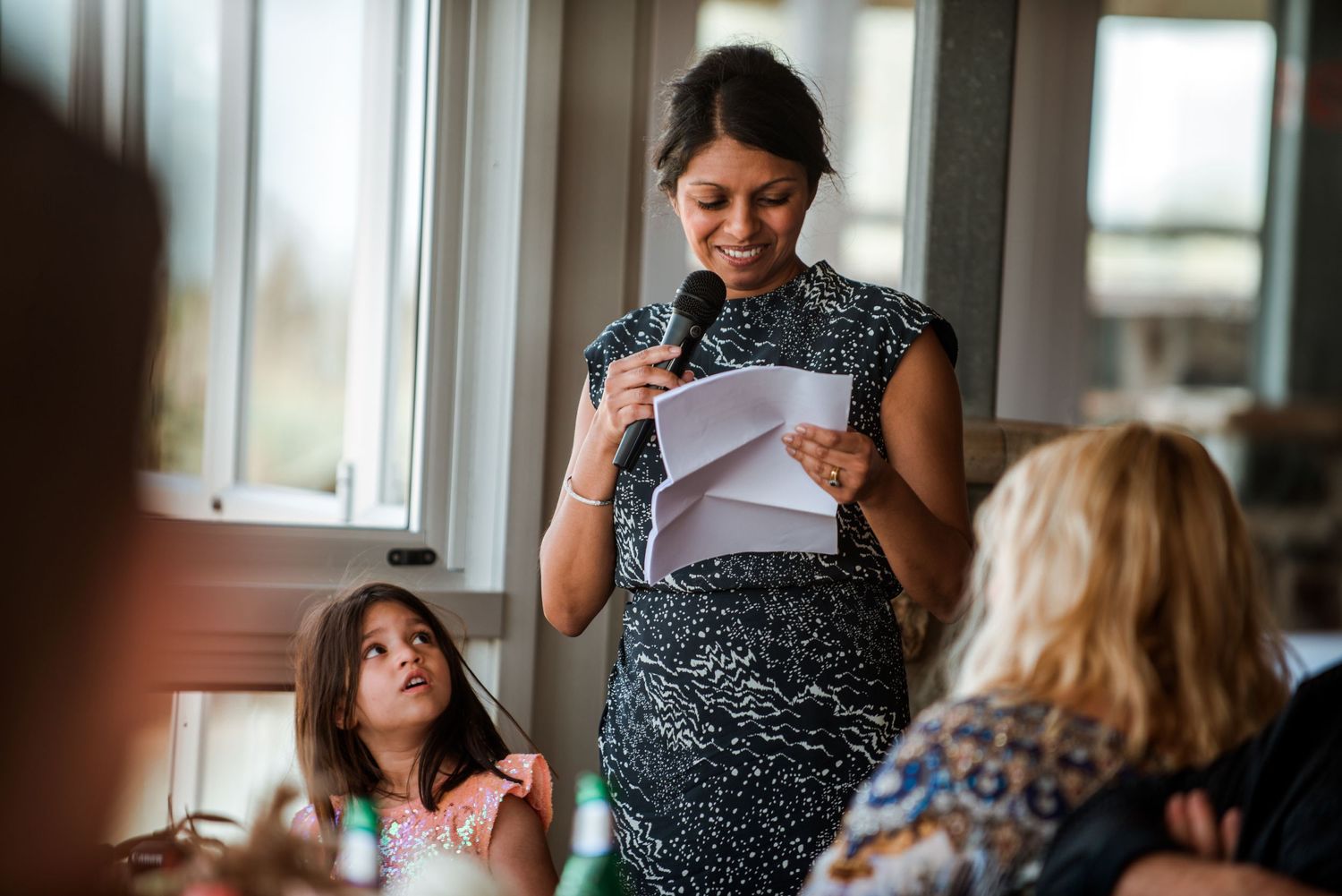 A speech being given at an intimate indoor gathering with guests seated around tables.