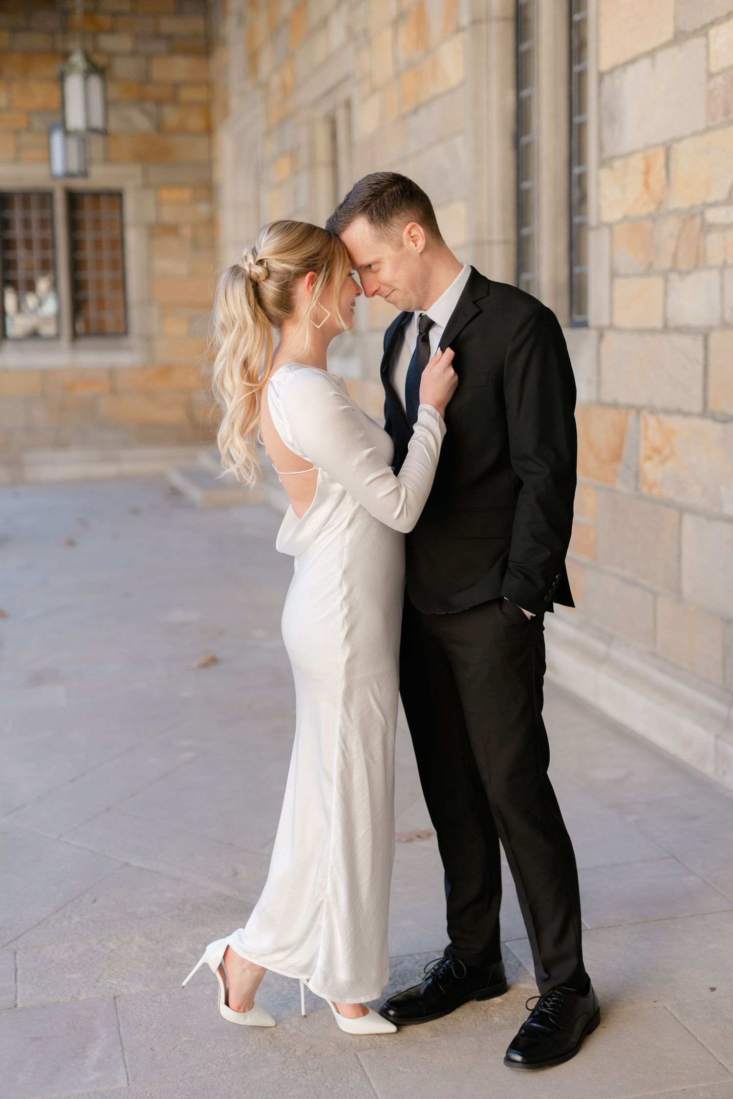 A bride and groom embrace and look lovingly at each other. Ann Arbor Law Quad Engagement Photos