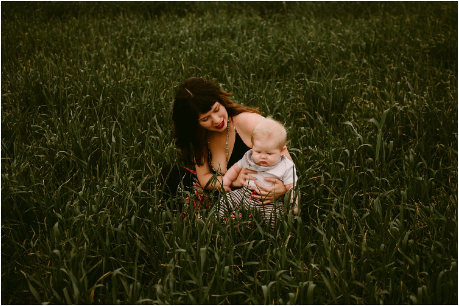 Artistic portrait taken in a lush grass field during golden hour.