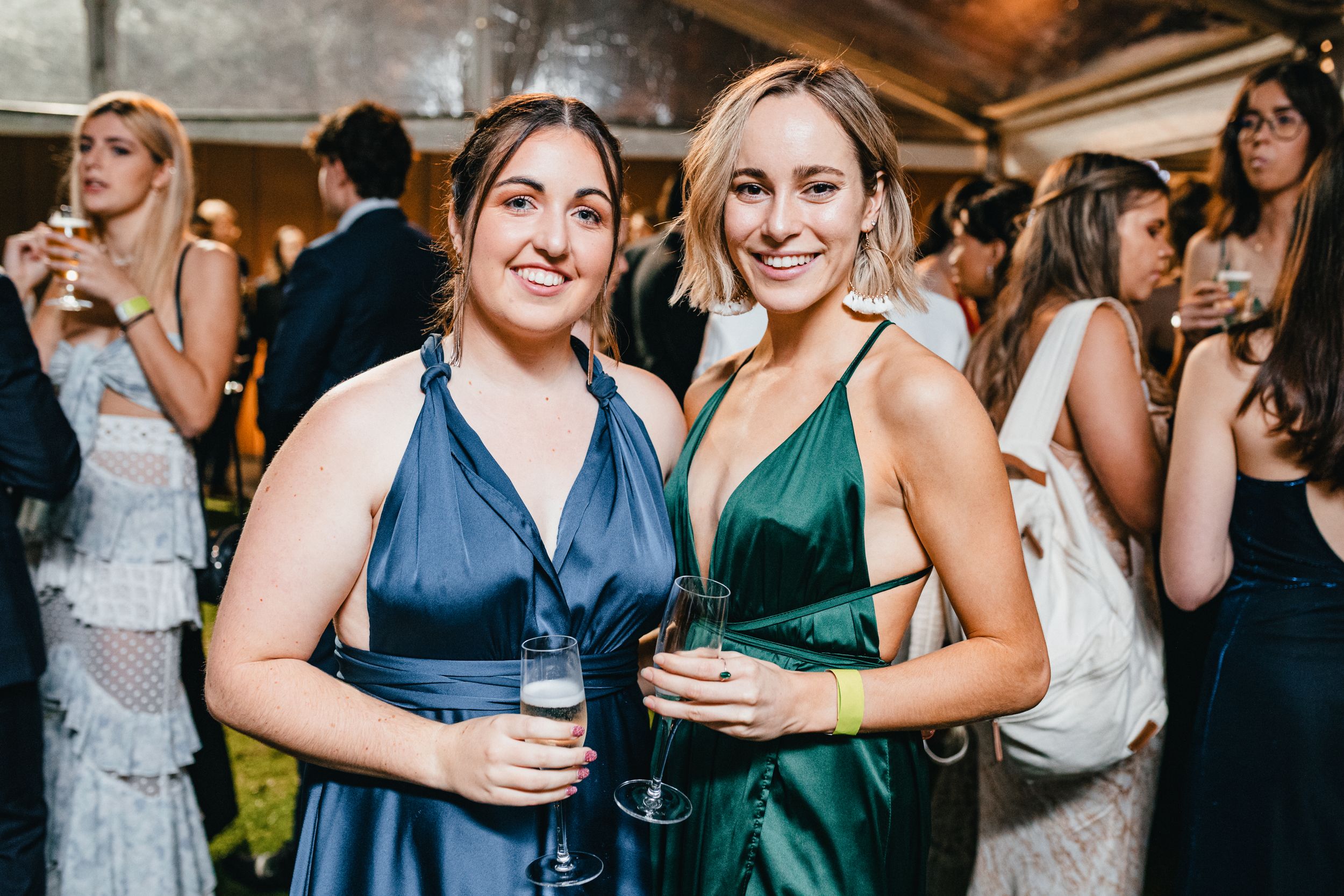 two elegant young women dressed in formal dresses attending a glamorous ballroom event