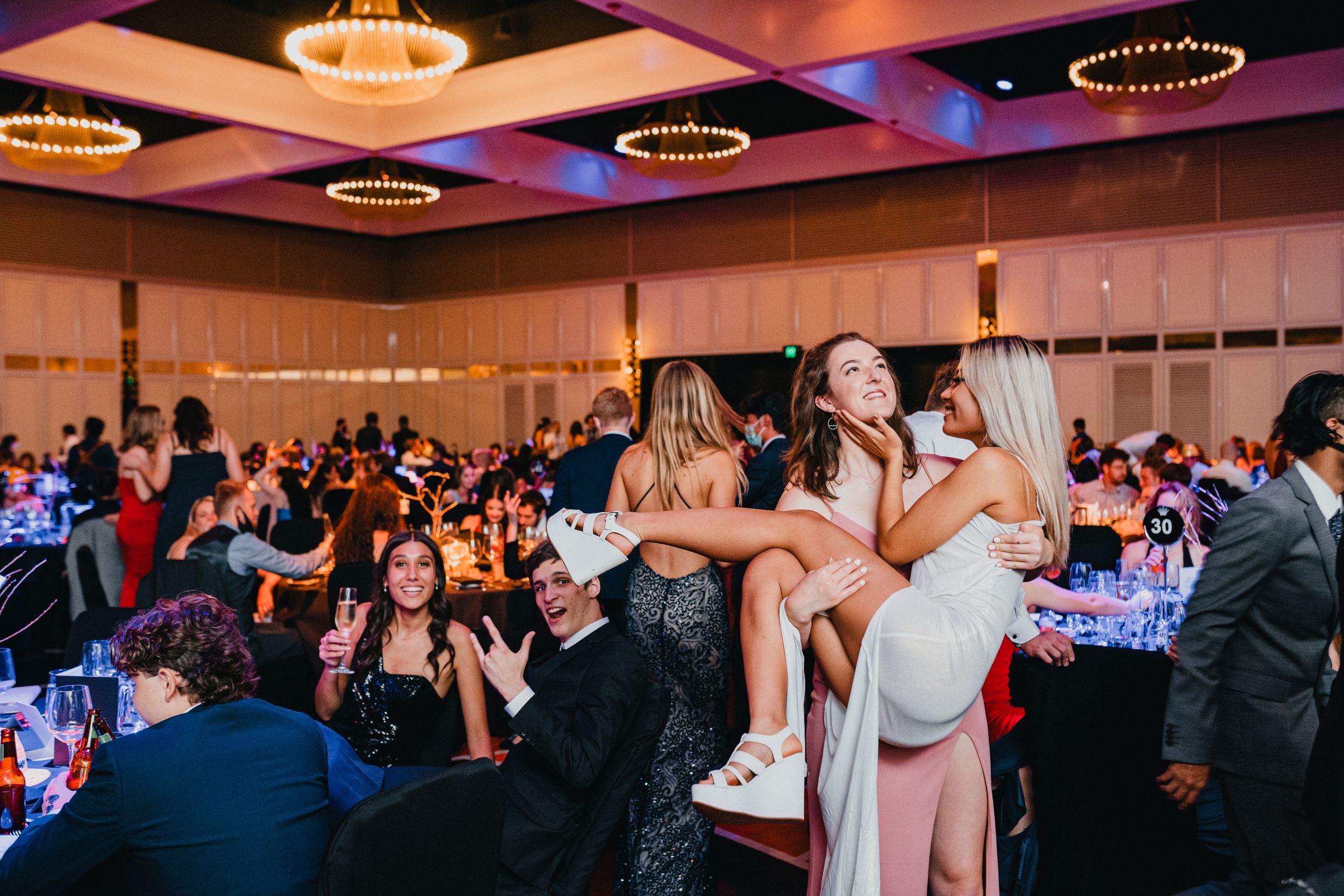elegant young women dressed in formal dresses attending a glamorous ballroom event