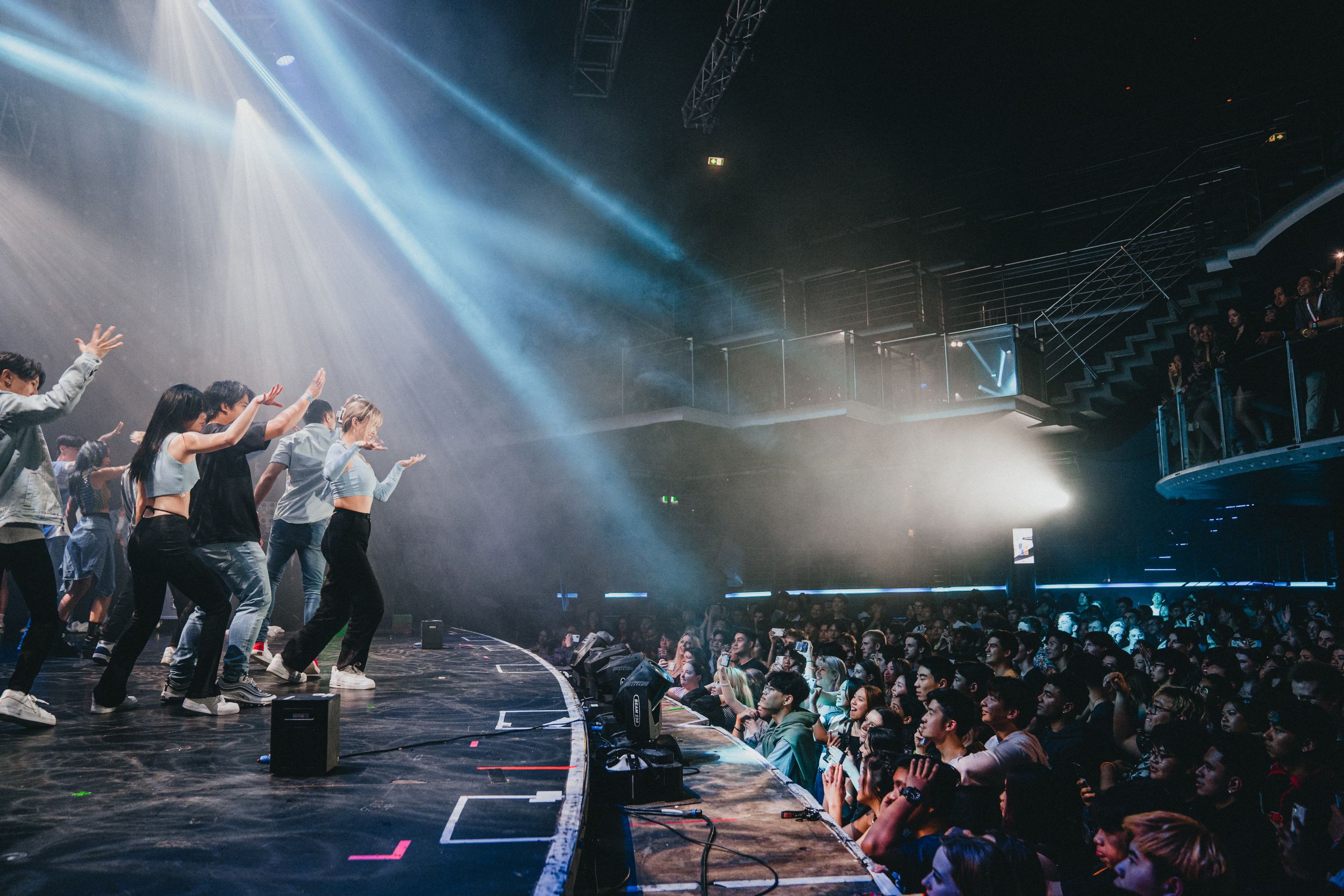 energetic dancing on stage with vibrant lights and music, high energy nightlife and entertainment