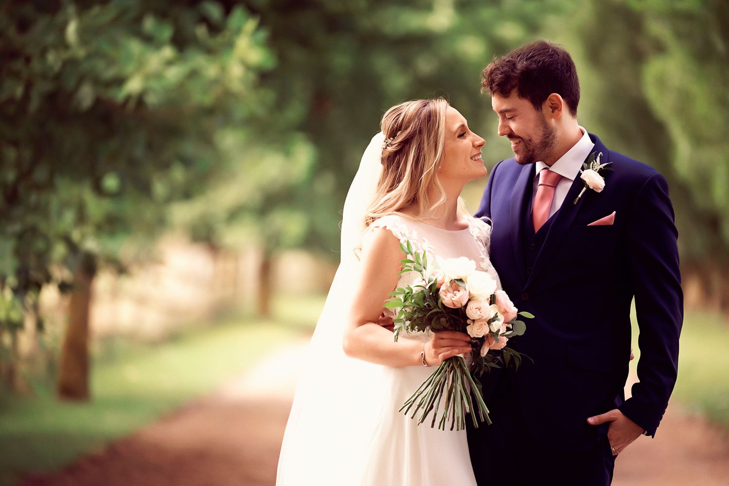 Romantic portrait of newlyweds in garden setting with soft bokeh effect.