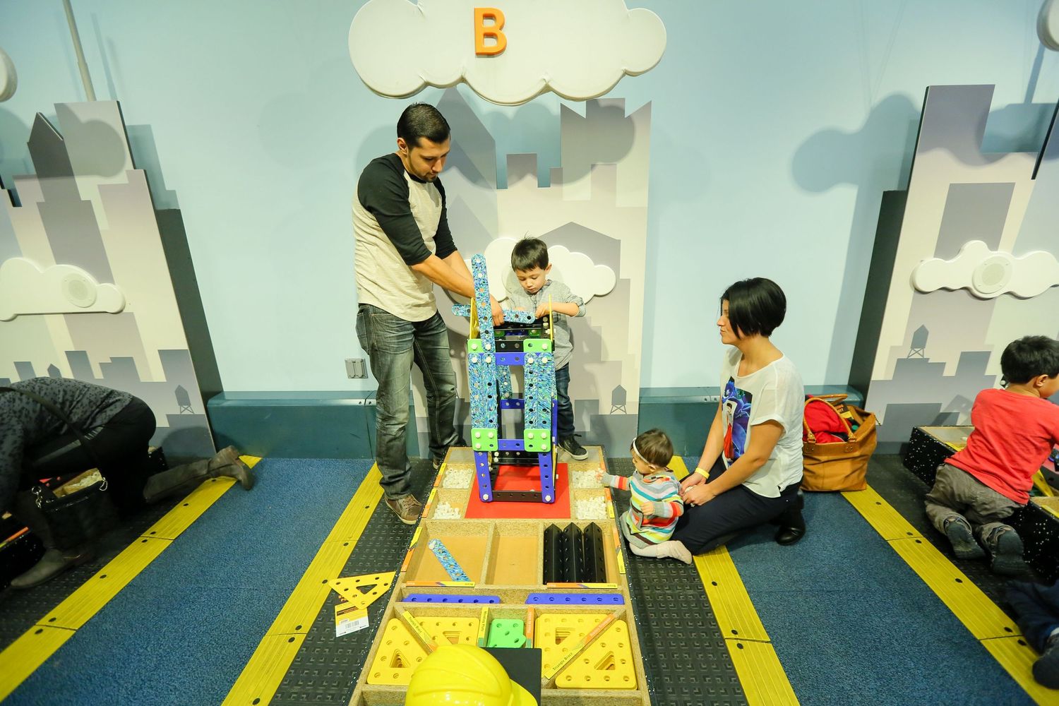 Children engaged in educational activities on colorful mats in a classroom setting.