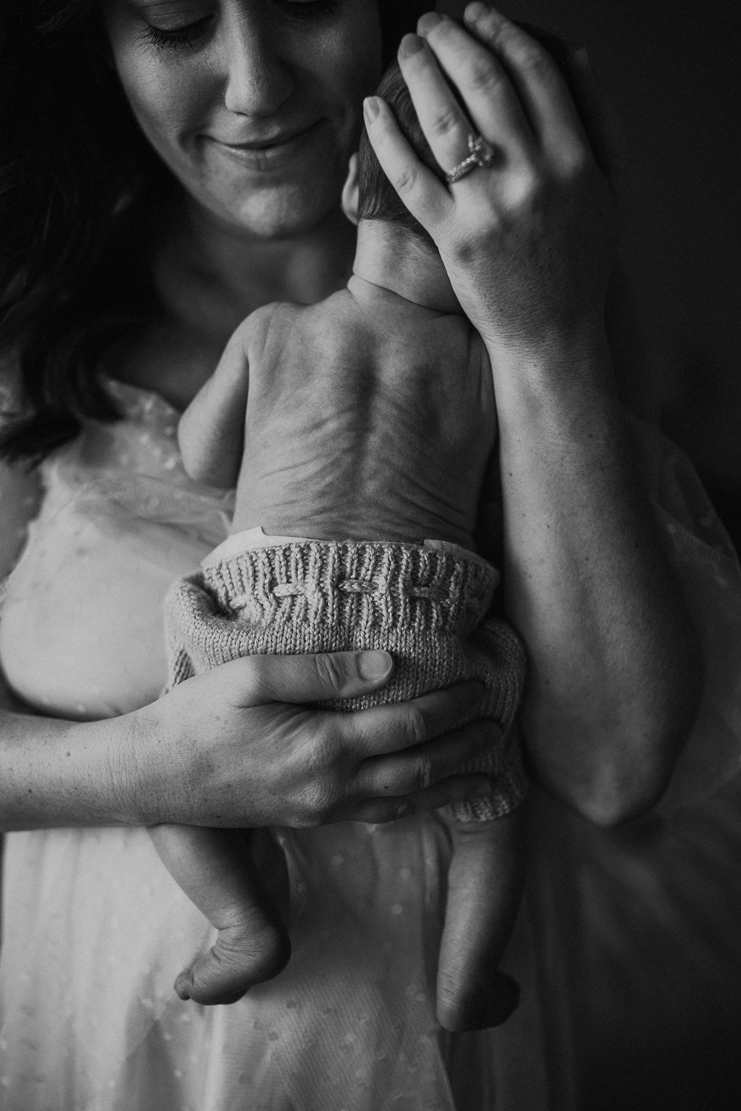 A mother holds her baby on her chest showing off his wrinkly skin.