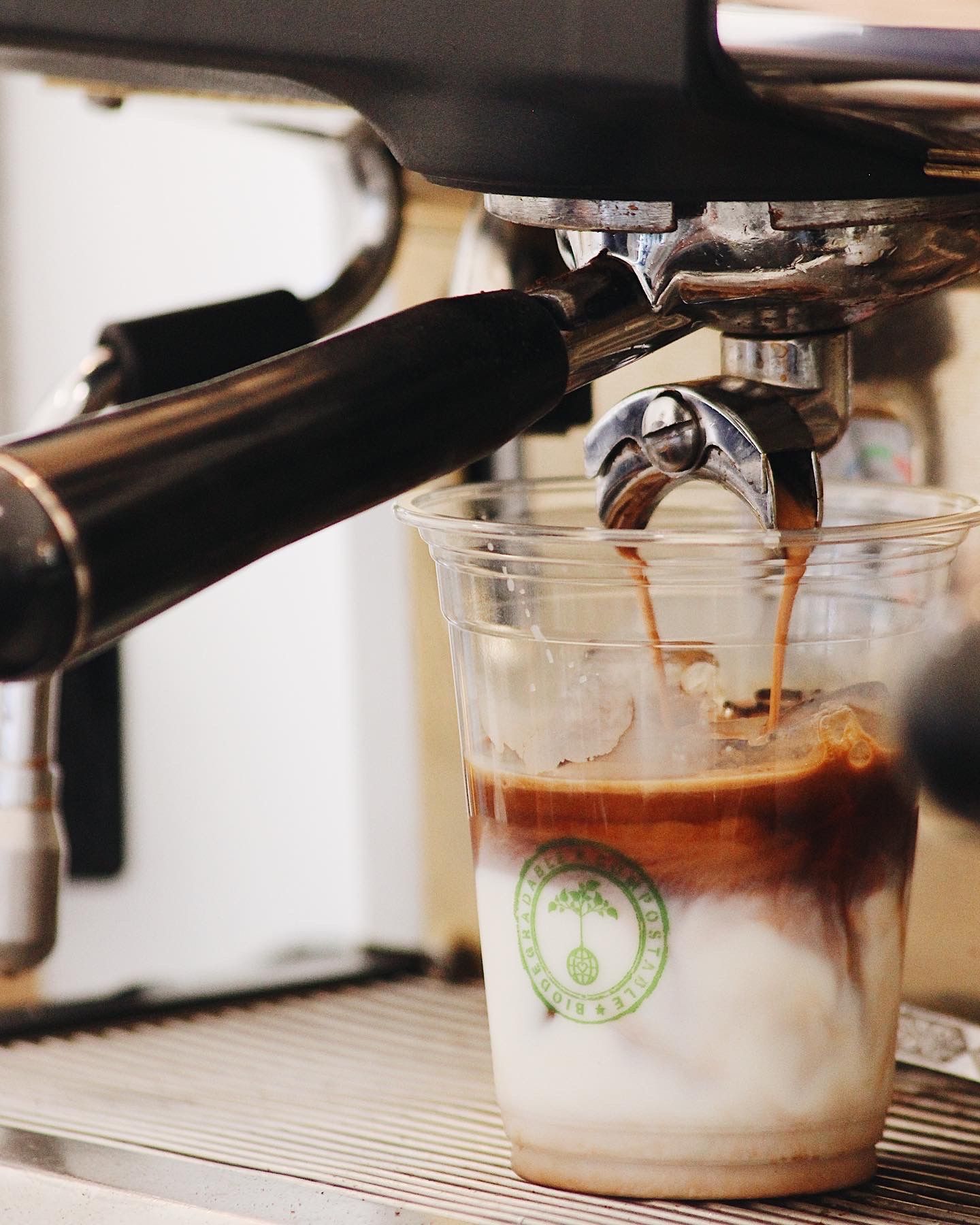 Espresso shot pouring into a clear glass cup with milk.