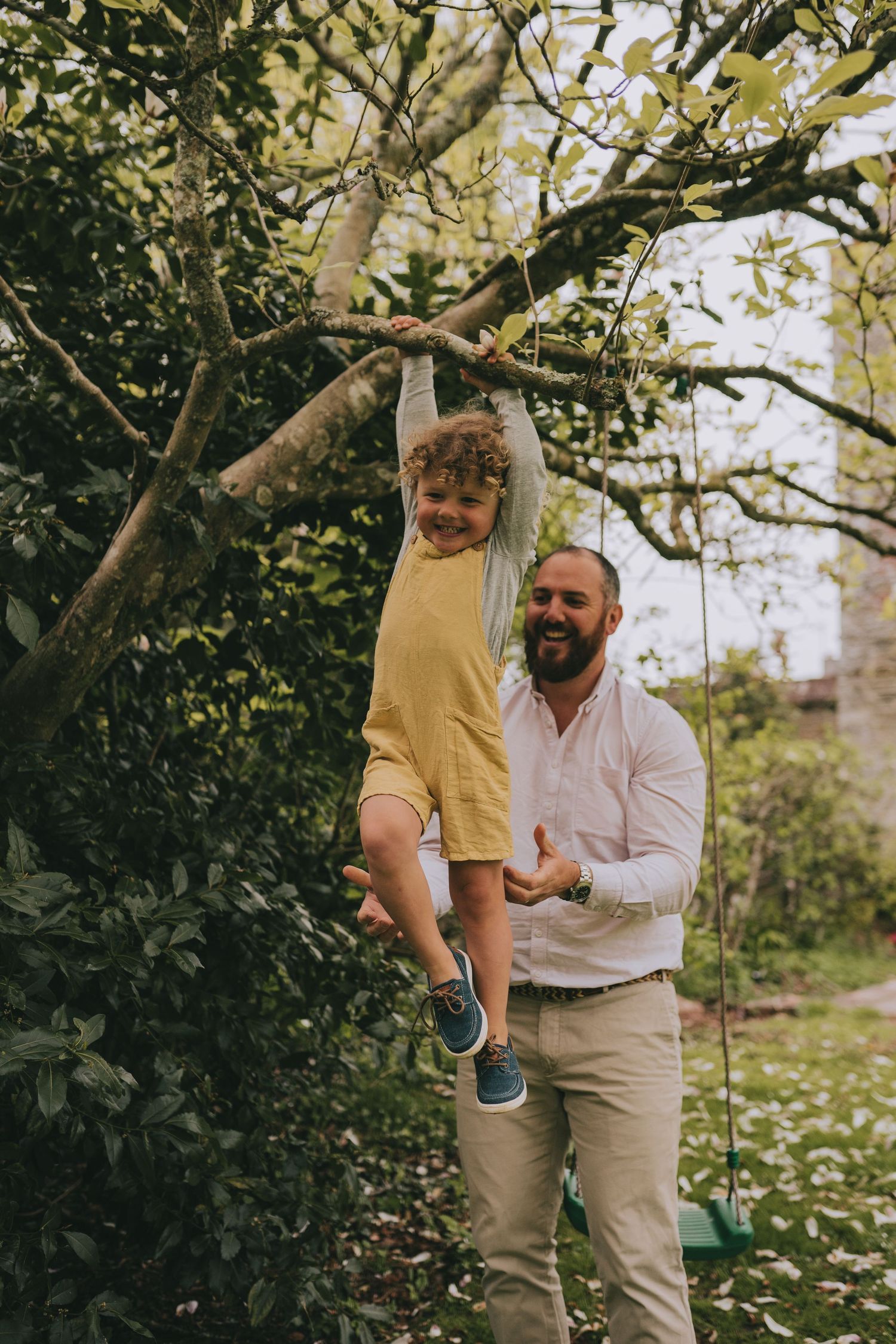 Playful outdoor moment with child climbing tree while supervised.
