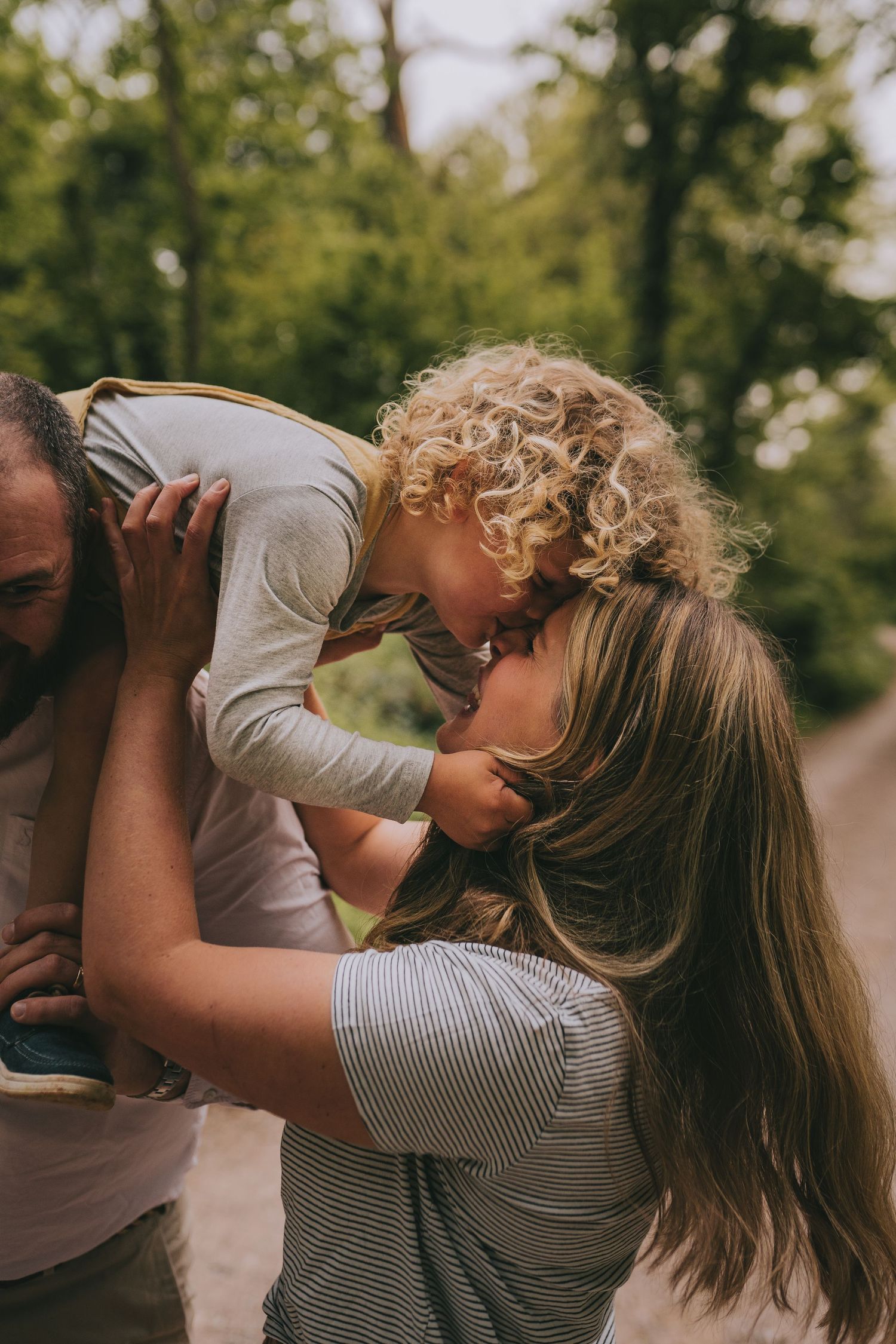 A tender moment shared between family members on a wooded path.