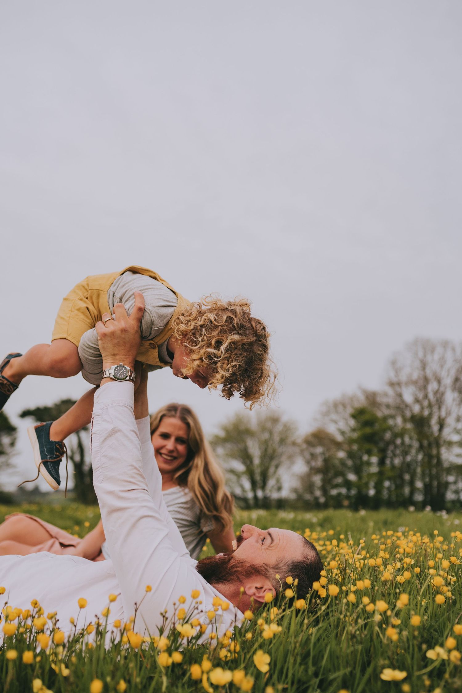 Playful family moment in a meadow of yellow flowers during springtime.