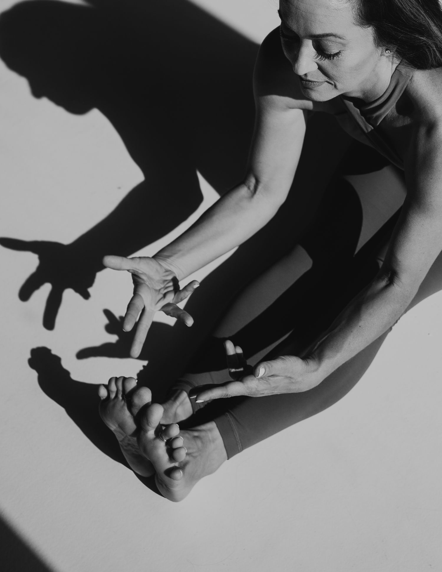 Artistic black and white image showing stretching and shadows cast on a white background.