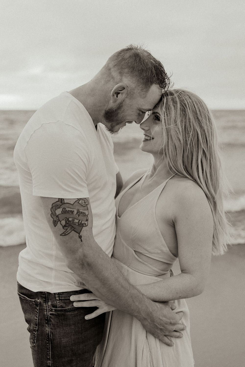 Black and white romantic beach portrait of couple in intimate embrace.