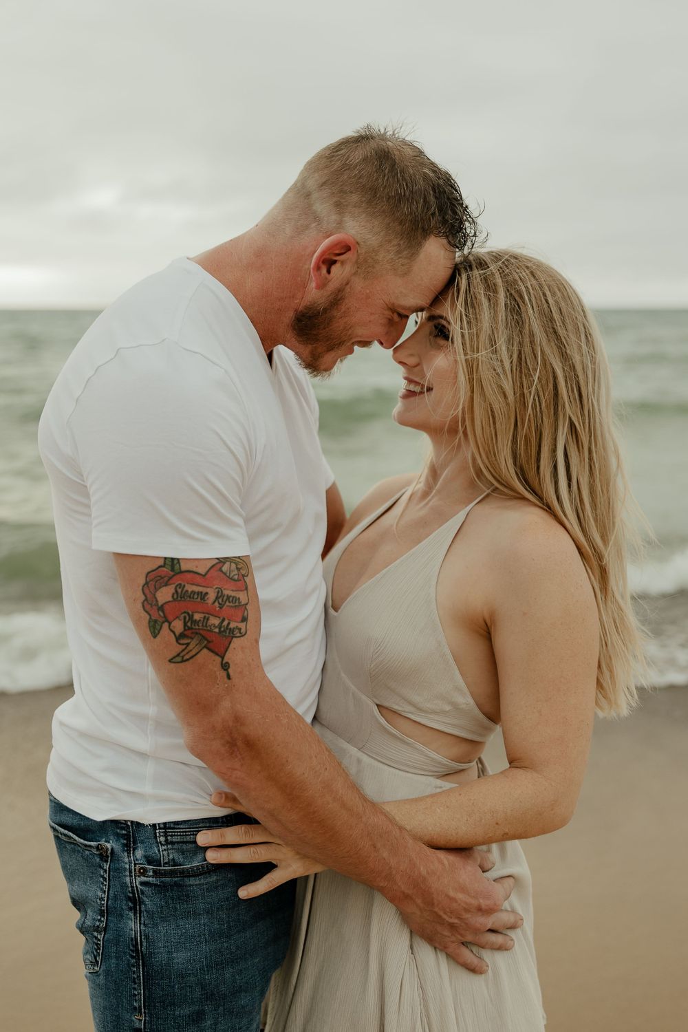 Close up beach portrait of couple sharing intimate moment against ocean backdrop.