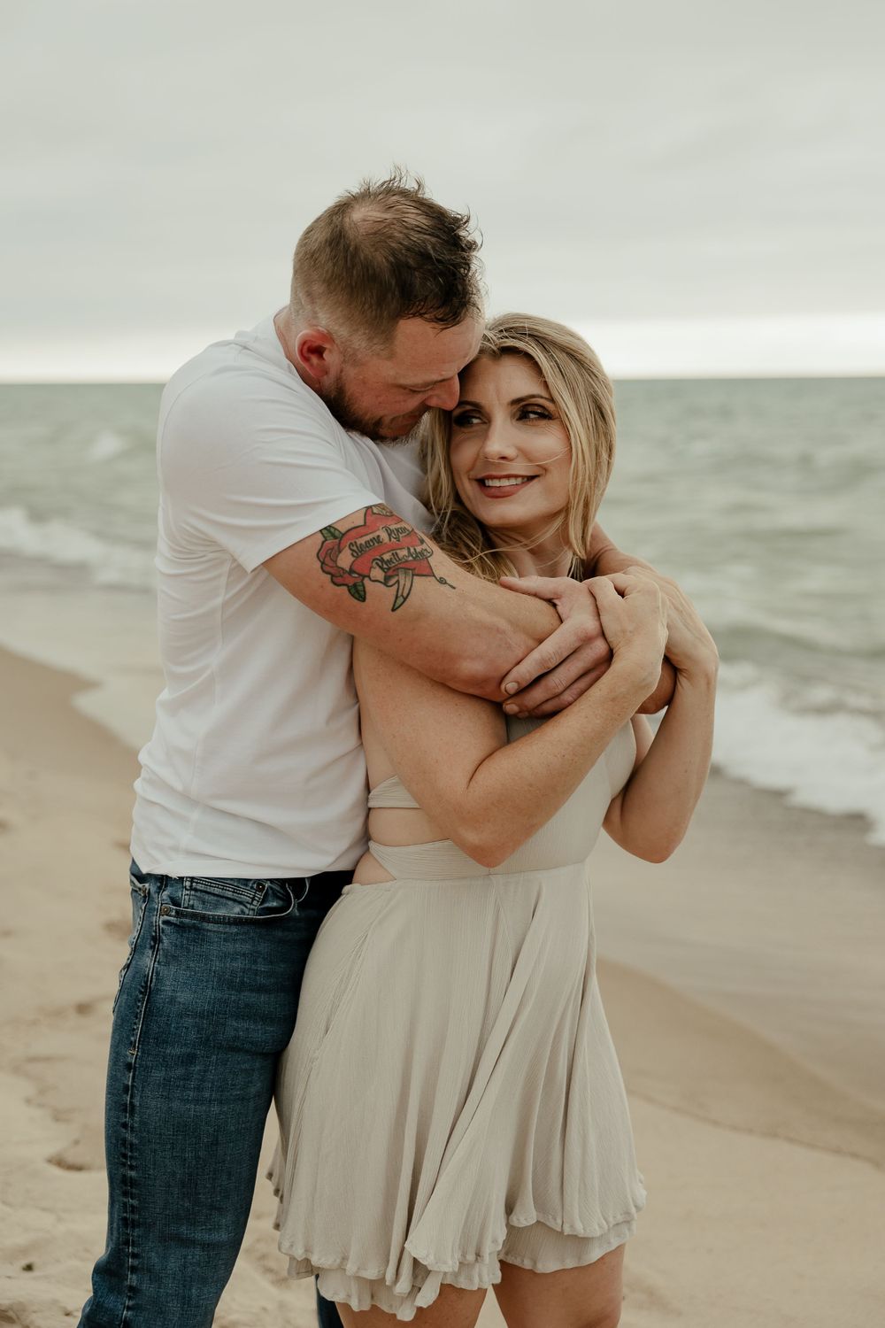A tender moment between a couple embracing on a misty beach shore.