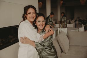 Two people in wedding attire sharing a joyful embrace during preparations.